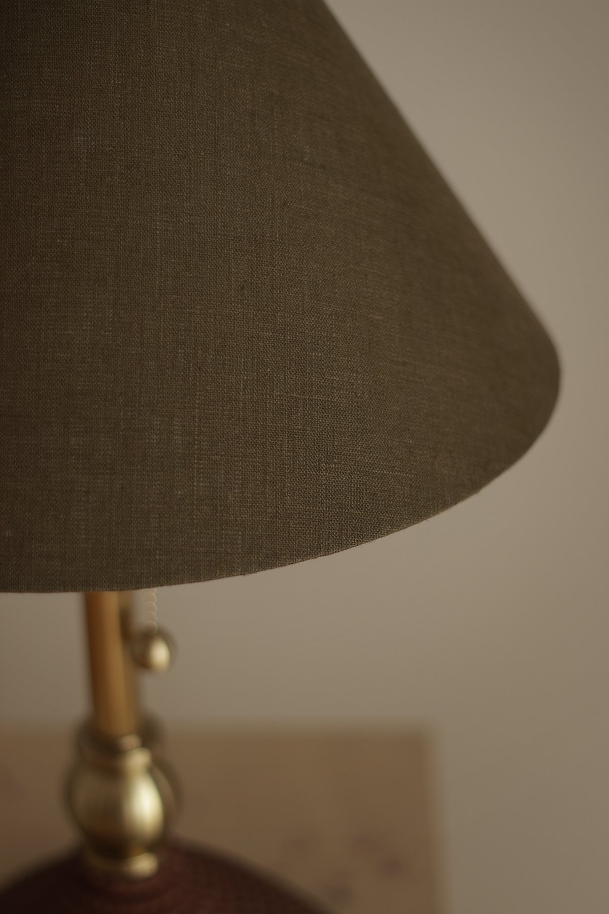 Close-up of green linen lampshade against a light background.