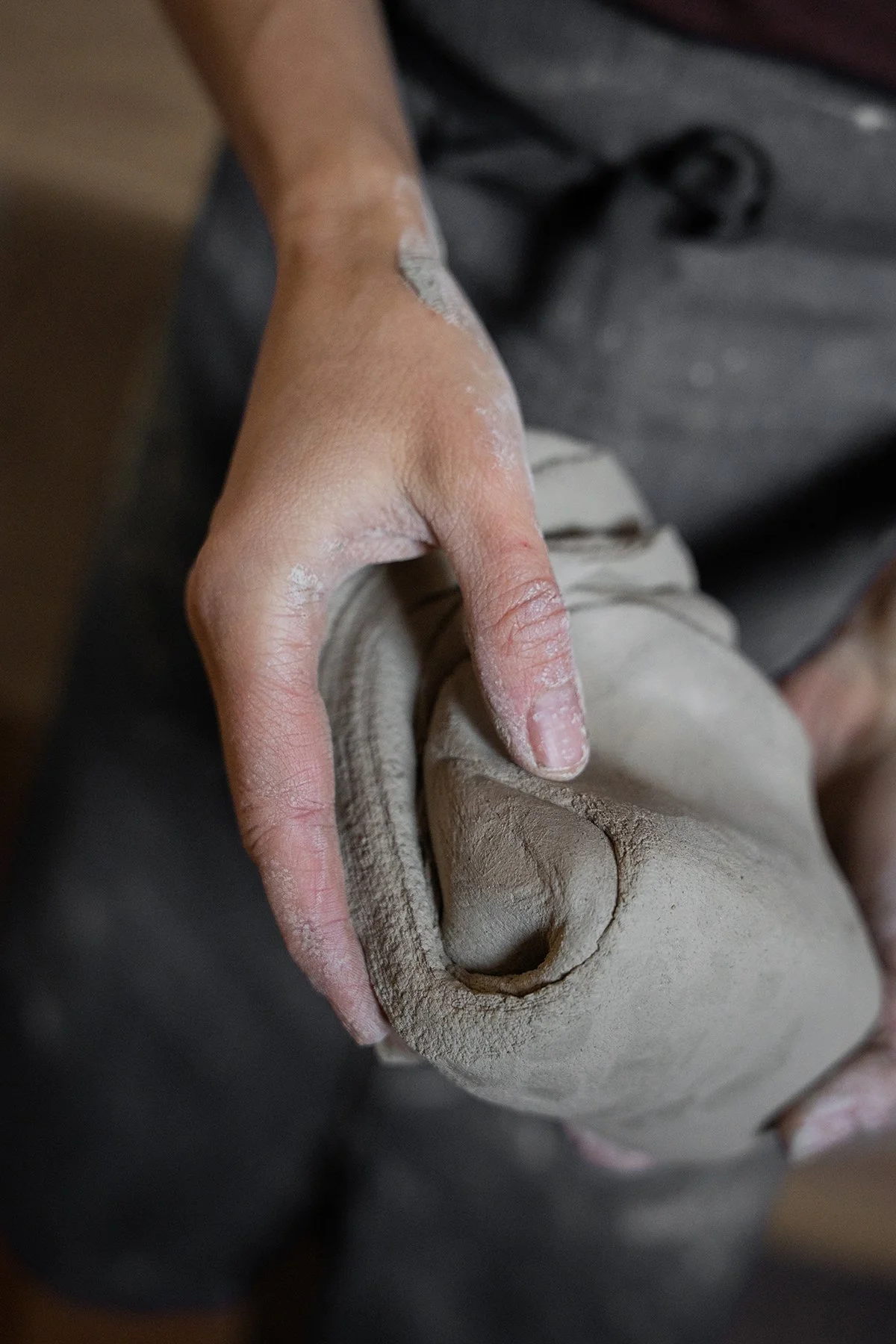 A person shaping clay on a pottery wheel in a pottery studio.