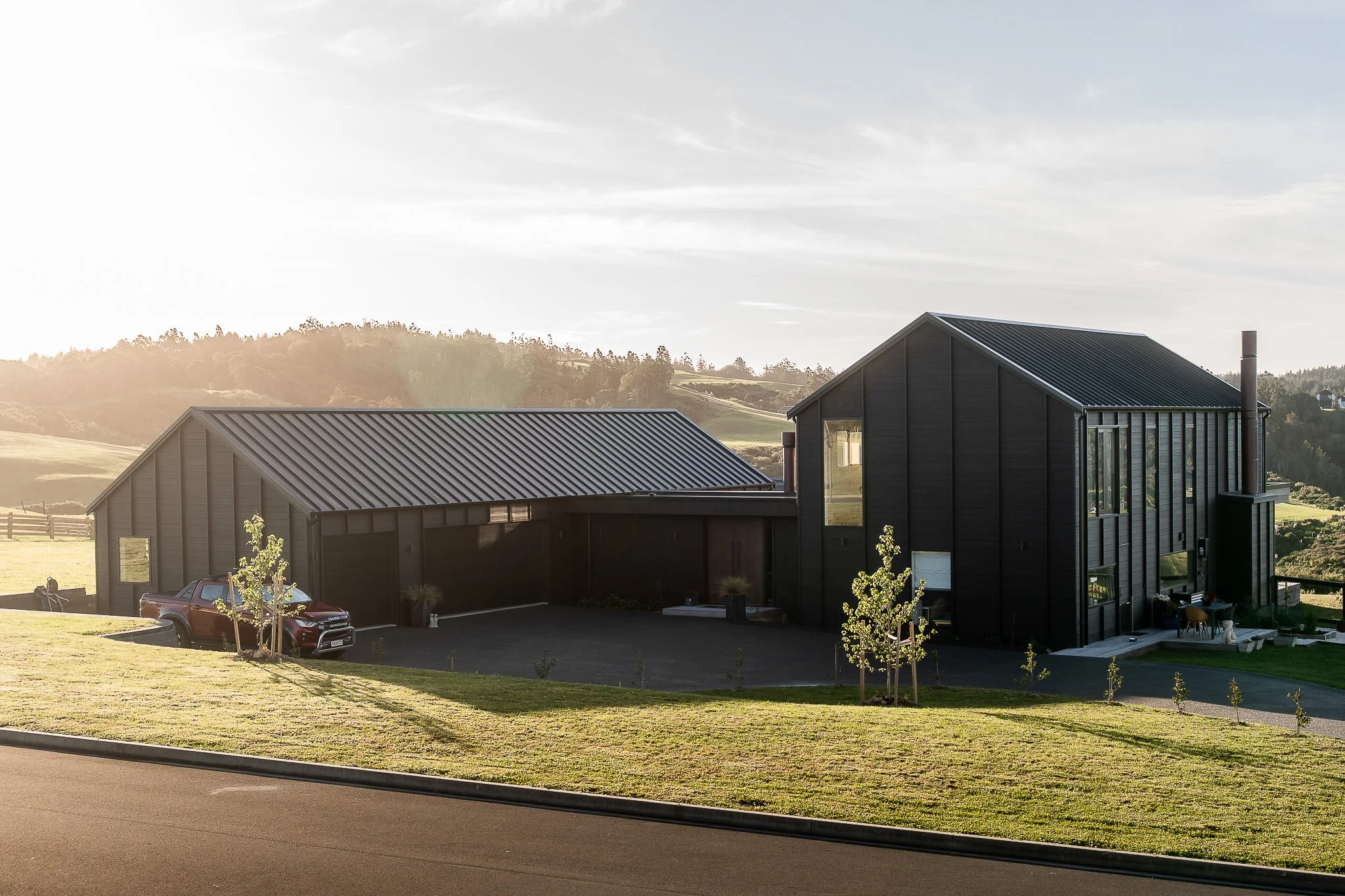 Modern barn style custom home build on Auckland’s Weiti Bay with black cedar batten cladding and full-height glazing.