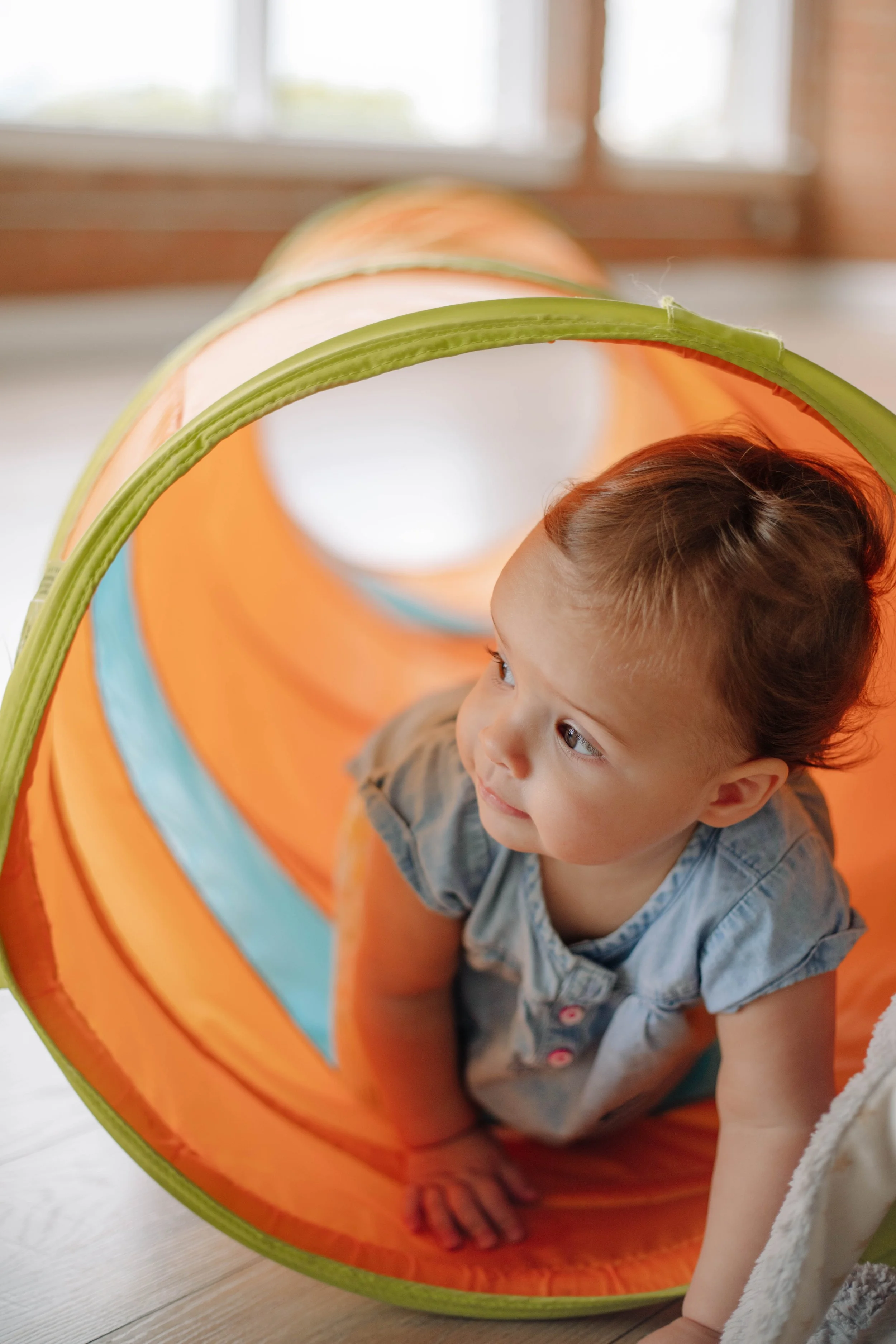 A woman and a girl playing a colorful stepping stone game indoors on a wooden floor, with a plain white wall in background.