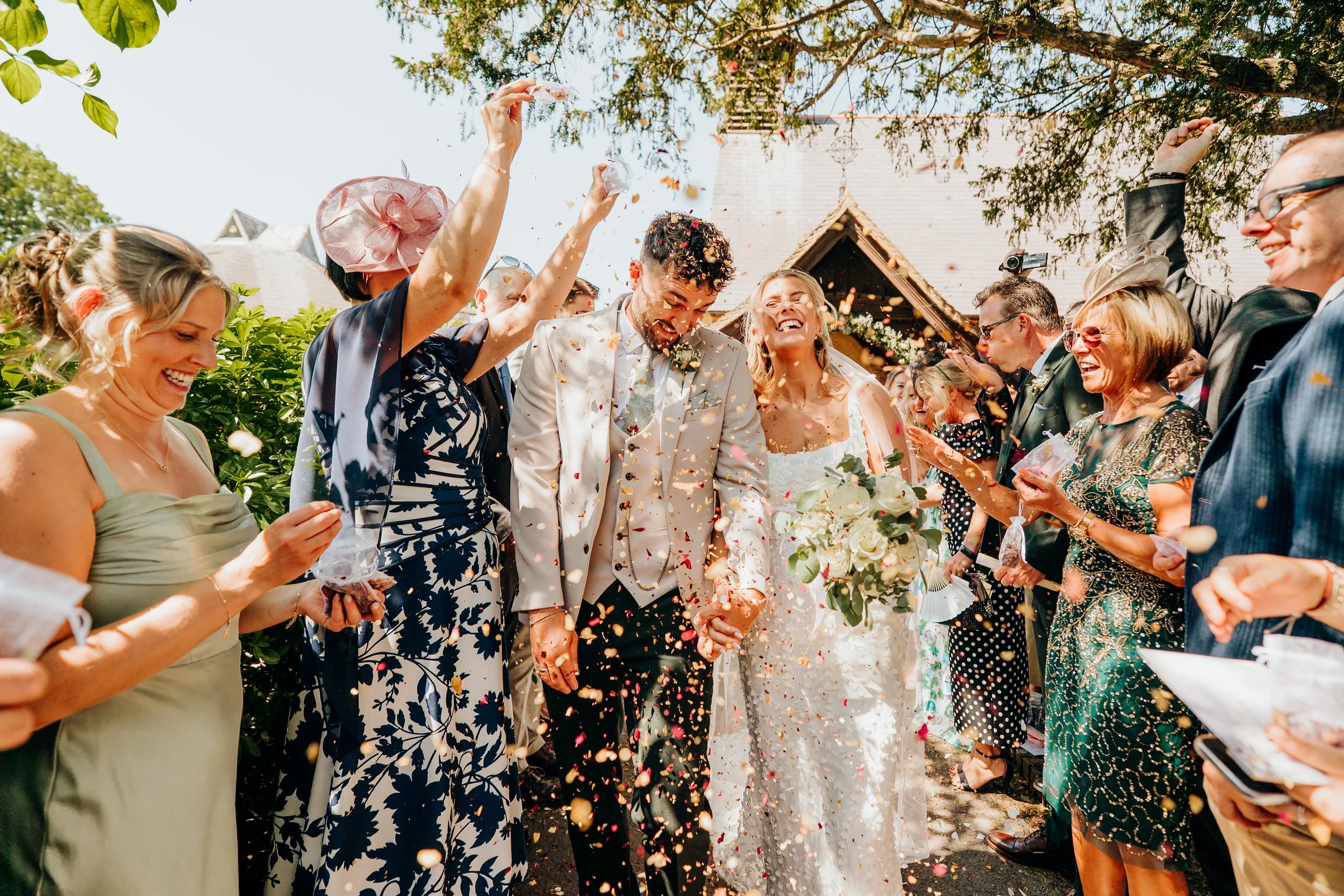 Bride and groom confetti exit at their Surrey wedding, guests cheering