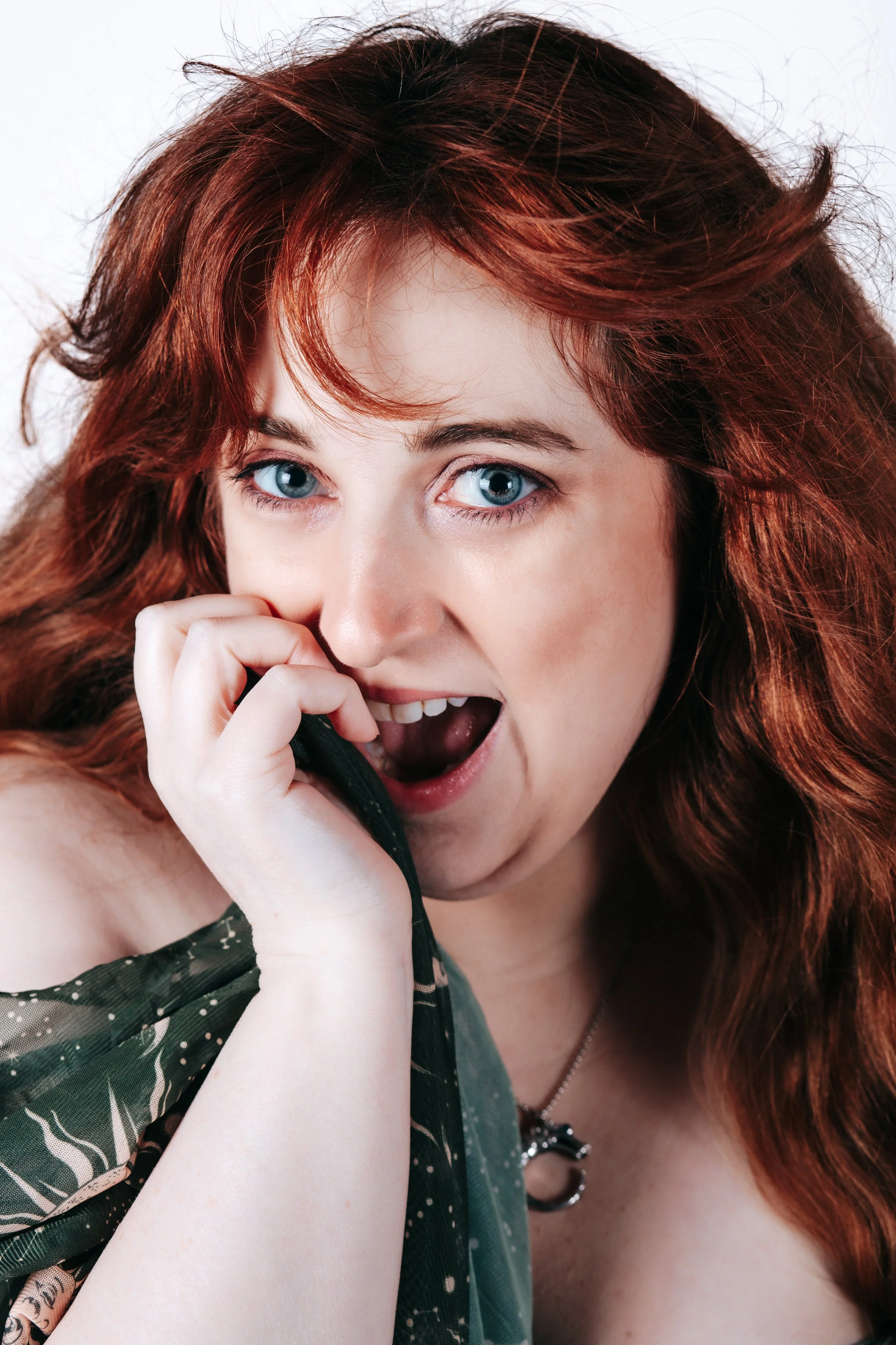 A woman with red hair and blue eyes holding a phone to her ear, appearing surprised or excited.