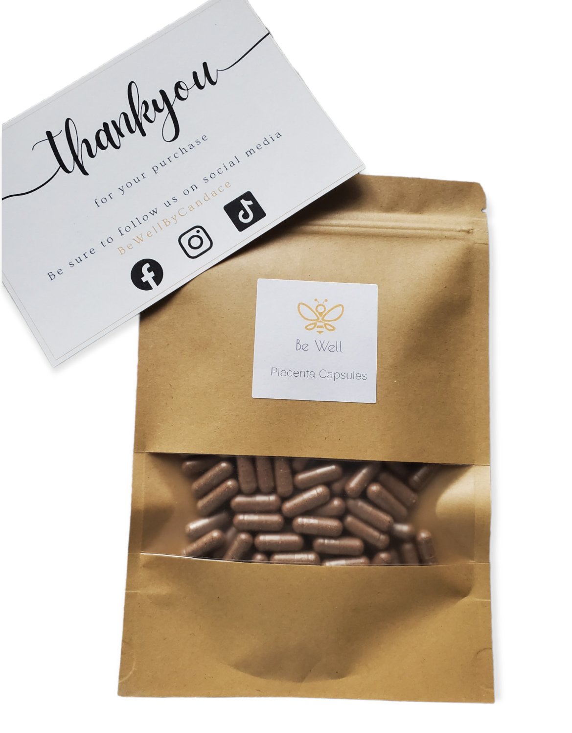 A brown paper bag labeled 'Be Well Placenta Capsules' with pink capsules visible through a transparent window, and a thank you card offering social media follow links for BeWellBYCandace along with an icon of a bee.