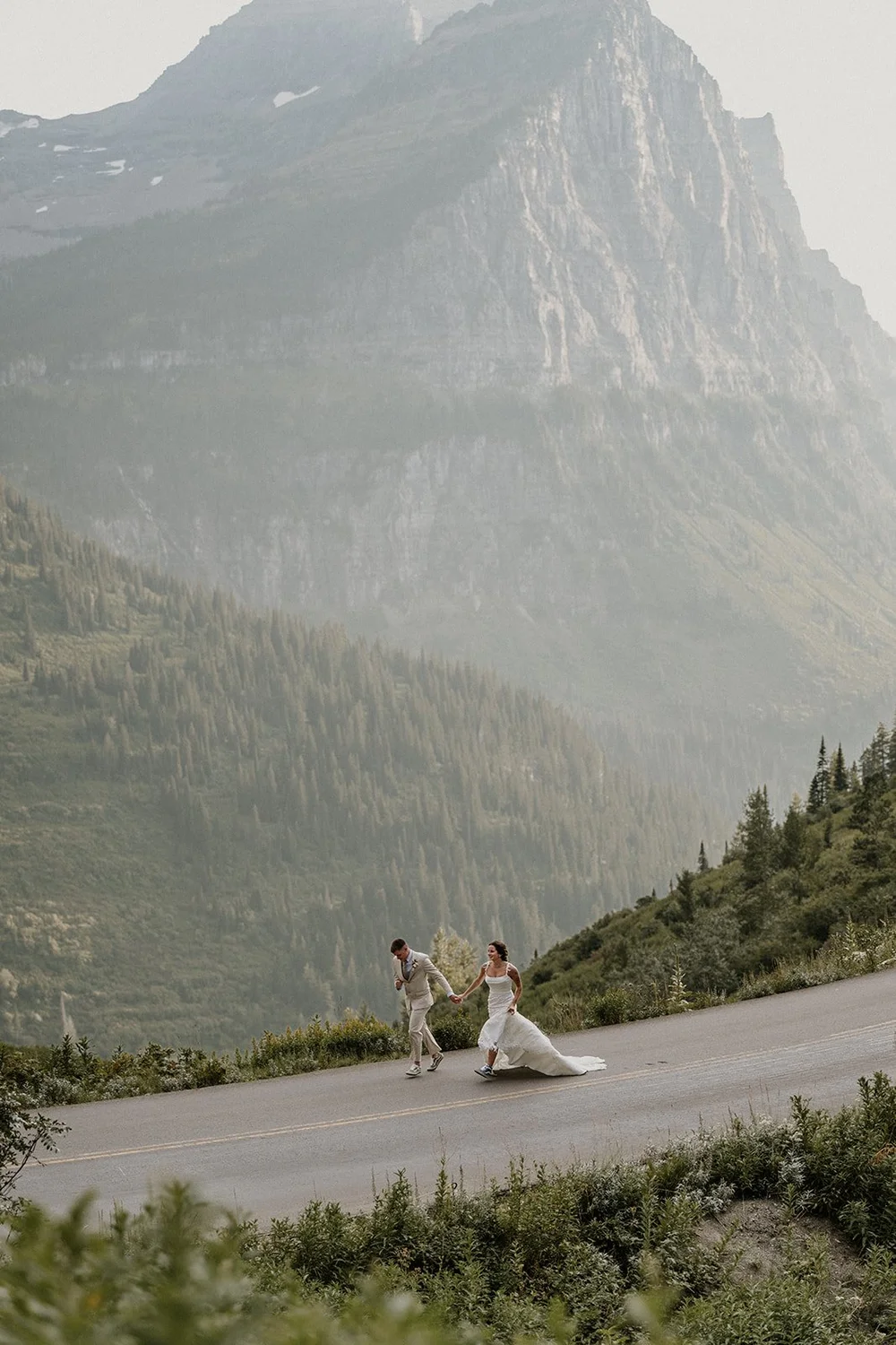 Couple walking a mountain road in Glacier National Park before their elopement vows