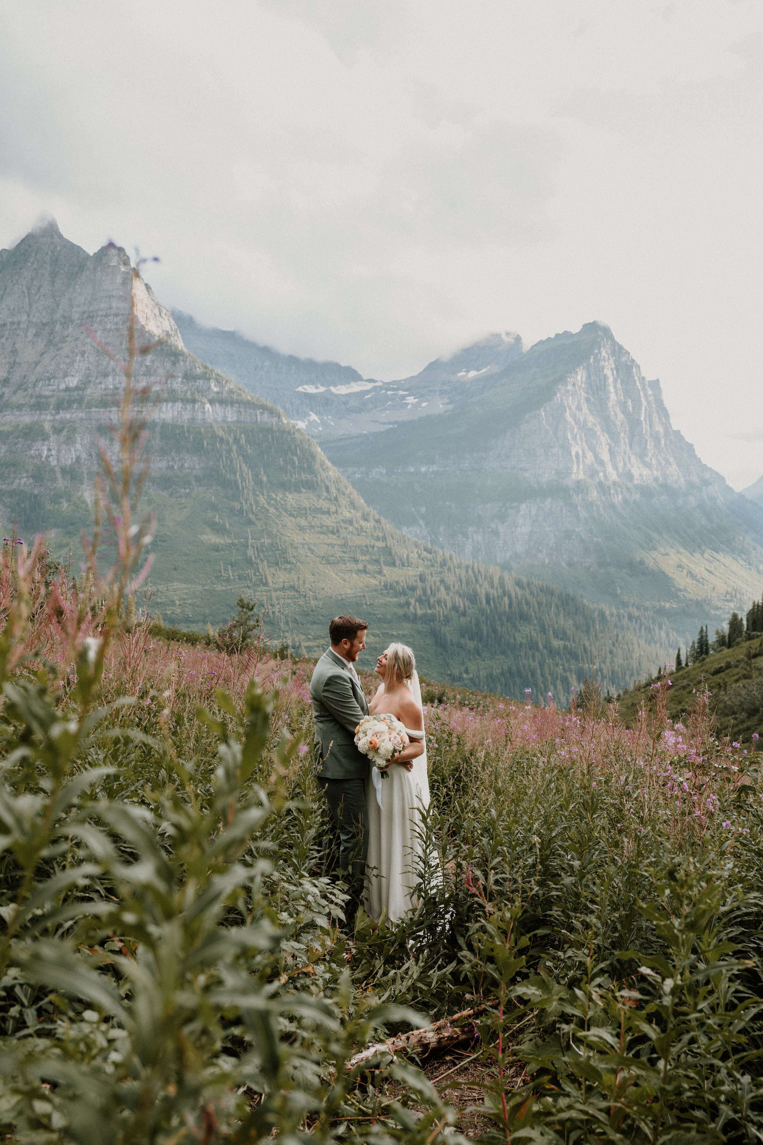 Bride and groom in a wildflower meadow beneath towering peaks