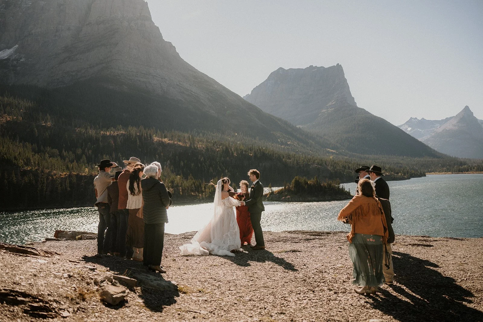 Lakeside wedding ceremony with friends and family and mountains behind
