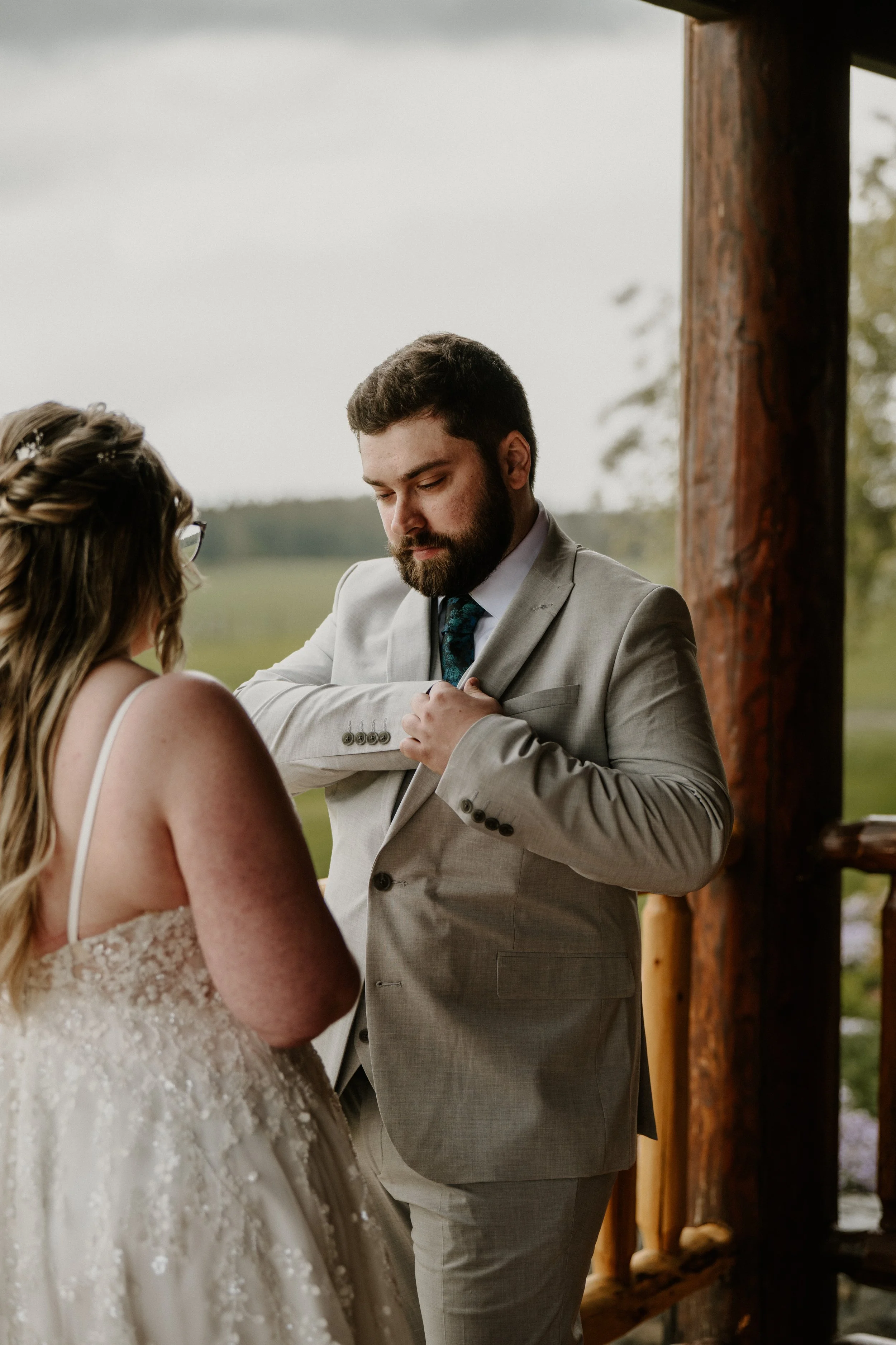 Alex in a light gray suit and Lily in a lace wedding dress stand together on the porch during their ceremony.