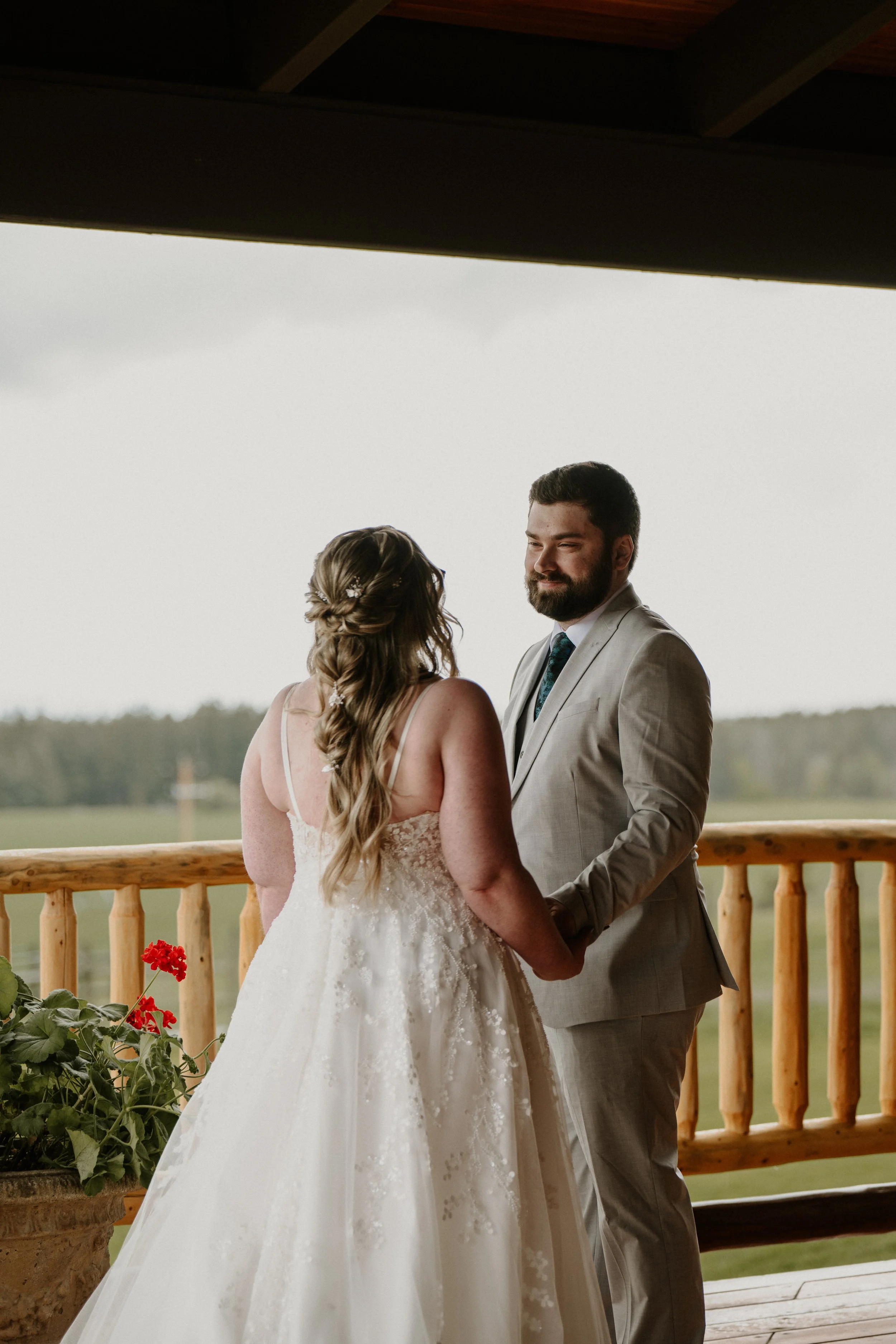 The couple holding hands on a wooden balcony during their wedding ceremony.