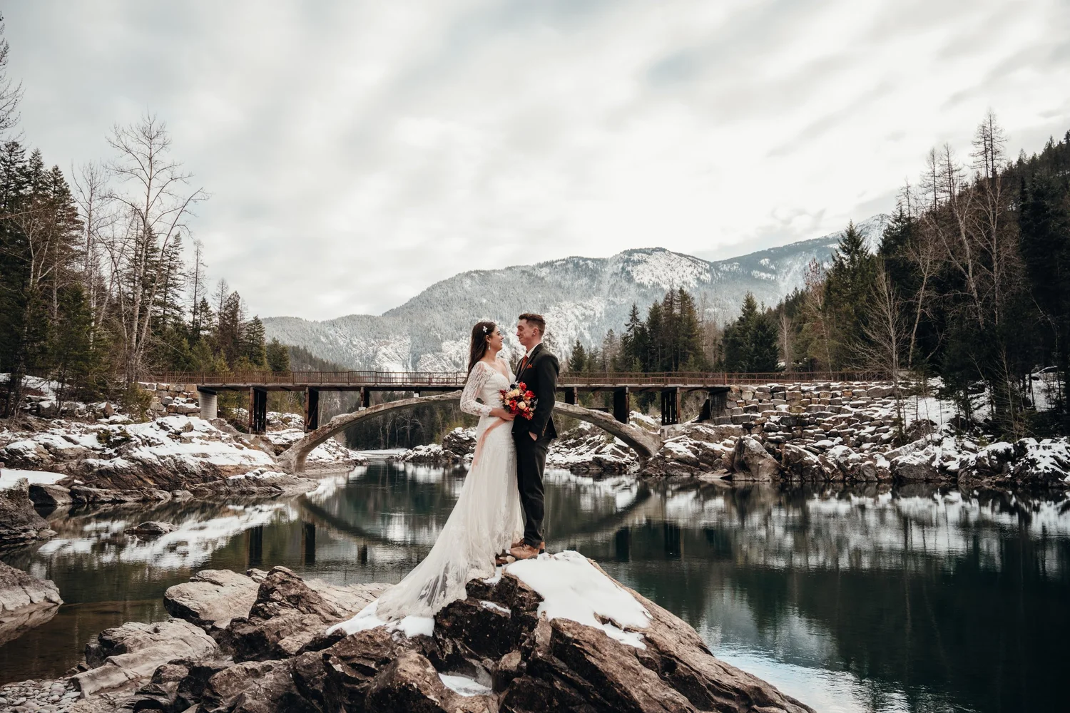 Winter portrait of newlyweds on the snowy Lake McDonald shoreline in Glacier National Park