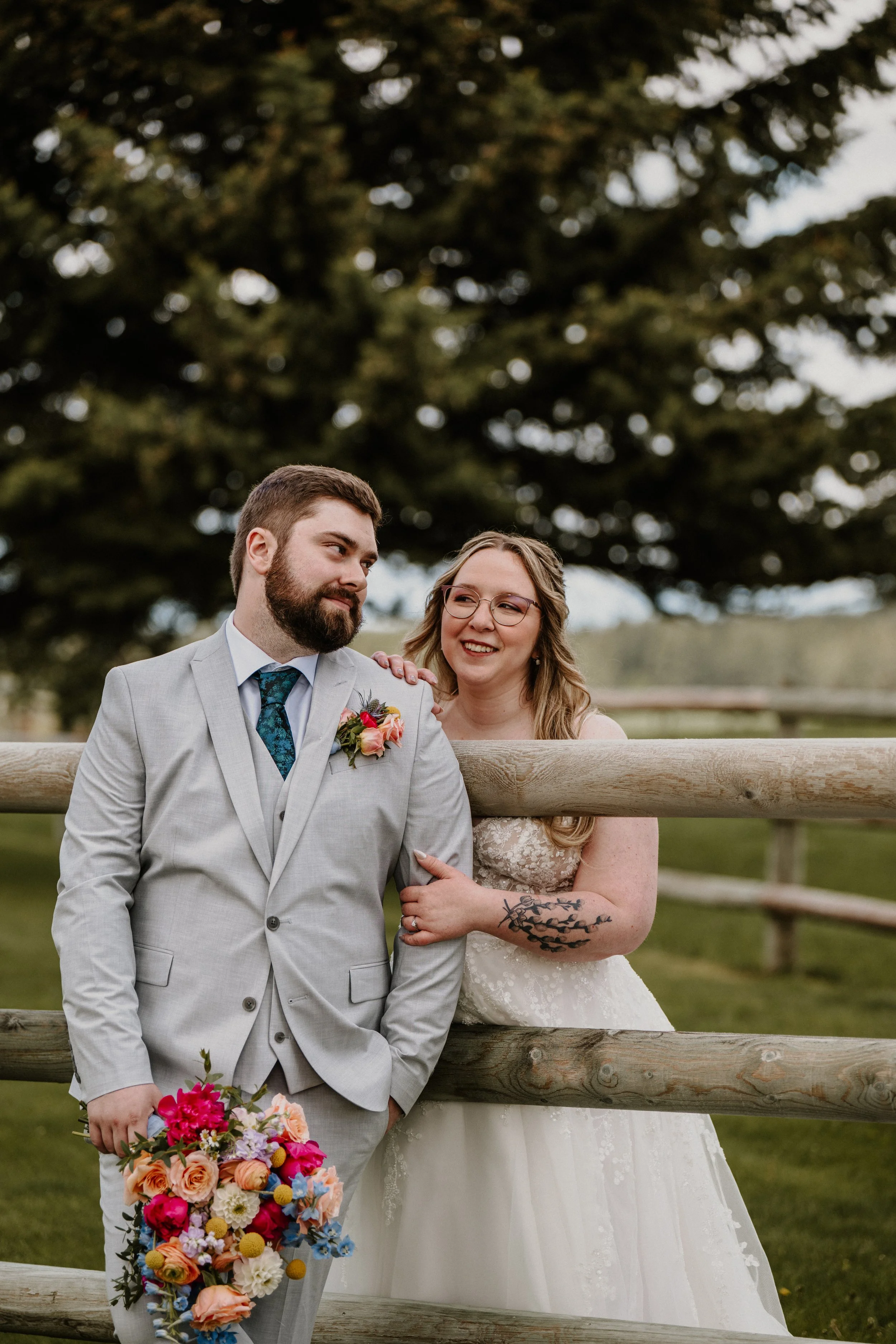 Alex and Lily smiling at each other near a wooden fence, Lily holding a colorful bouquet.