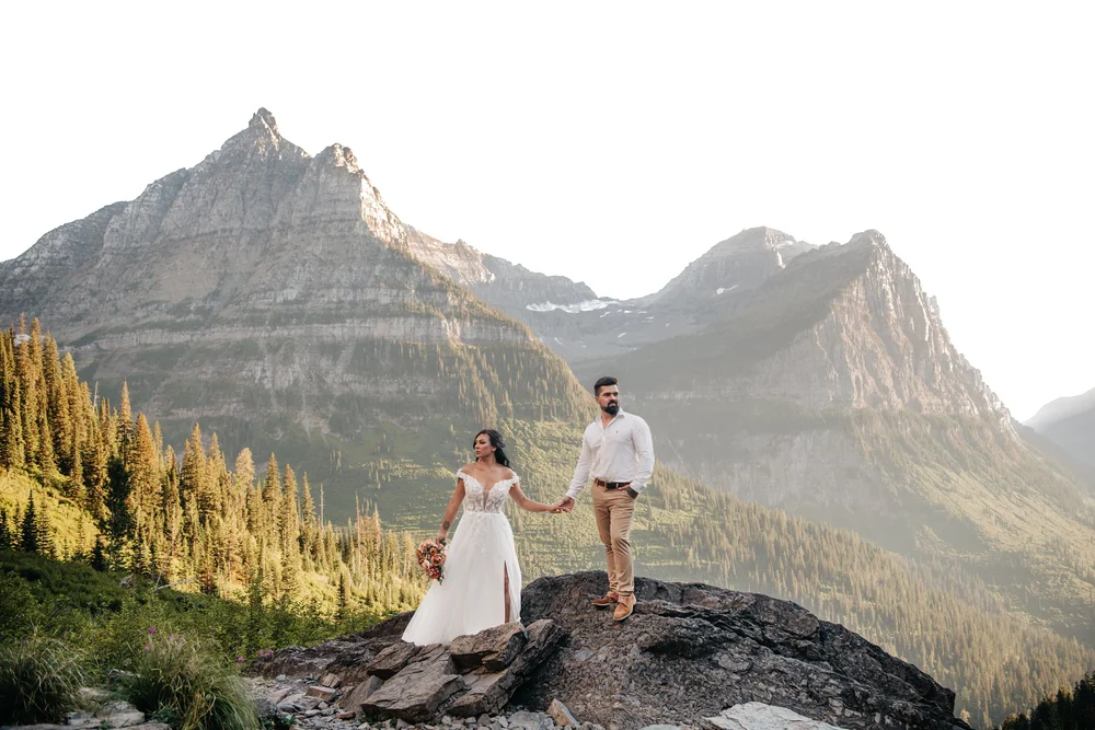 Couple holding hands on a rocky ledge at sunset in the Montana mountains