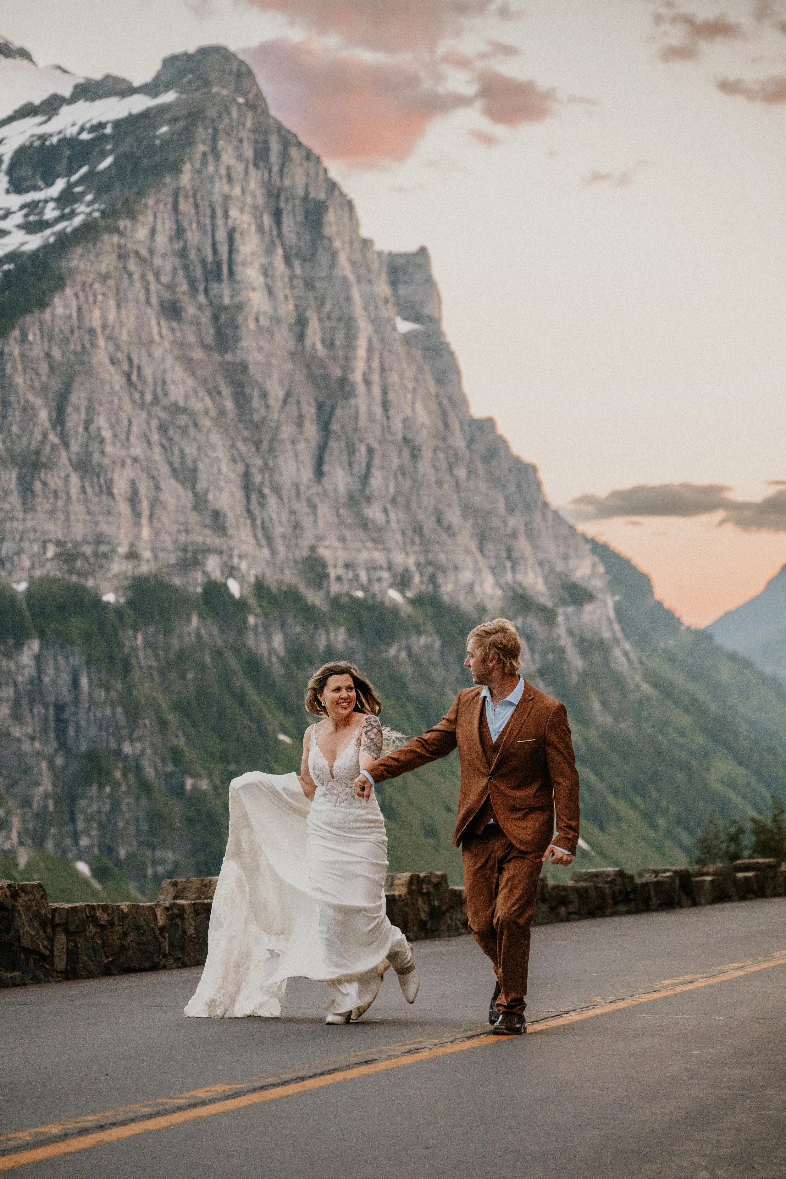 Couple running hand in hand on a mountain road at sunset