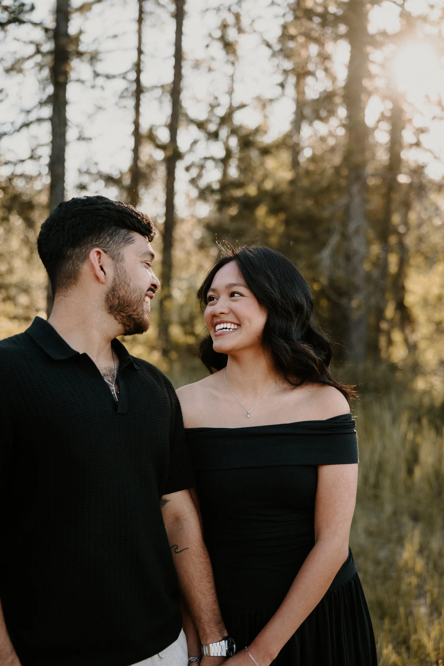 Engaged couple smiling at each other in a Montana forest at golden hour