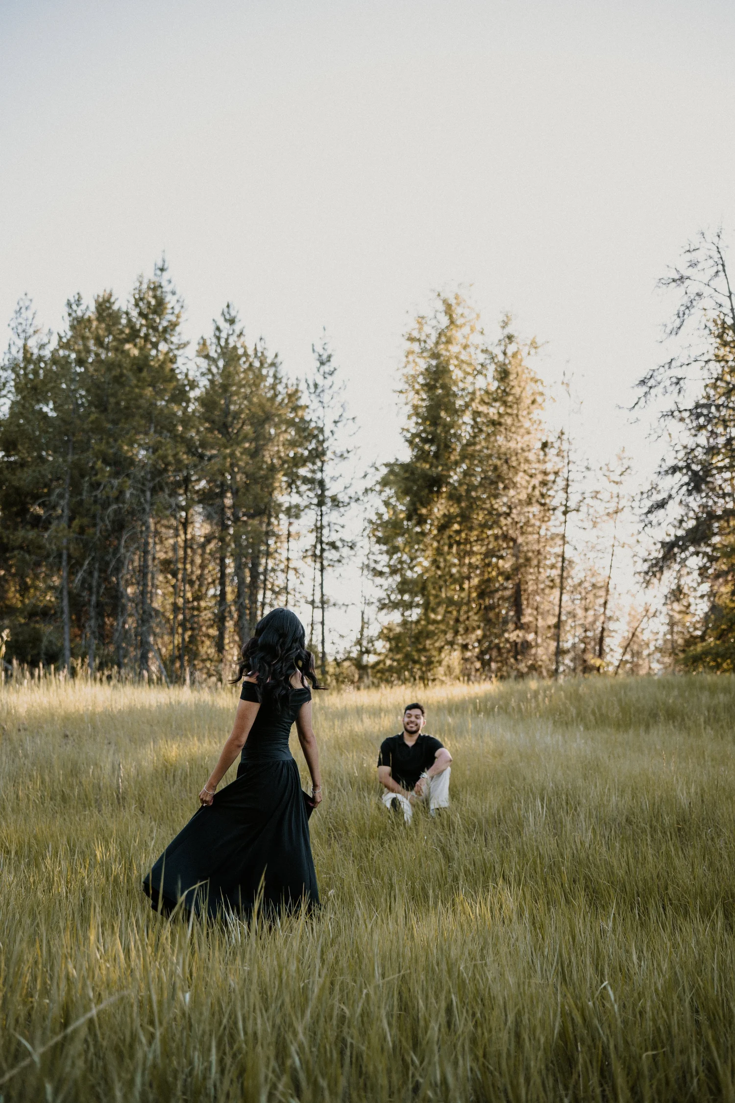 Couple in a grassy field in Glacier National Park during their engagement session