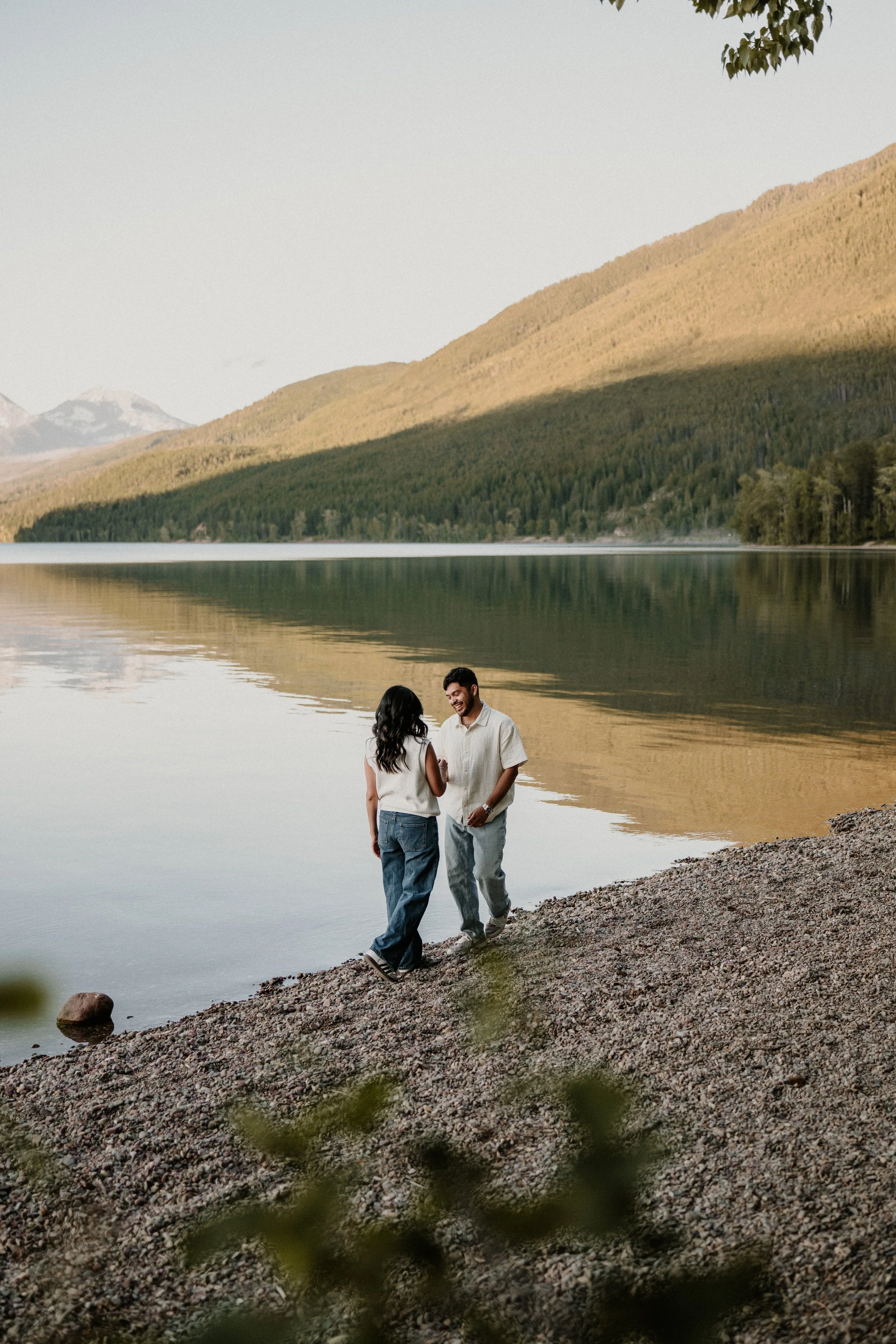 Couple walking along a rocky shore in Glacier National Park during sunset