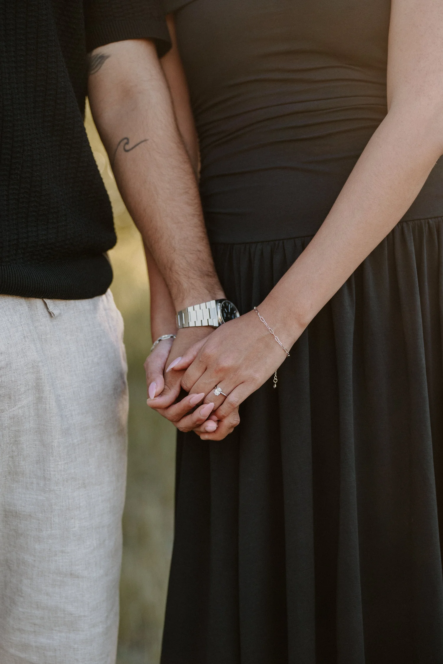 Close-up of a couple holding hands, woman wearing engagement ring, in Glacier National Park
