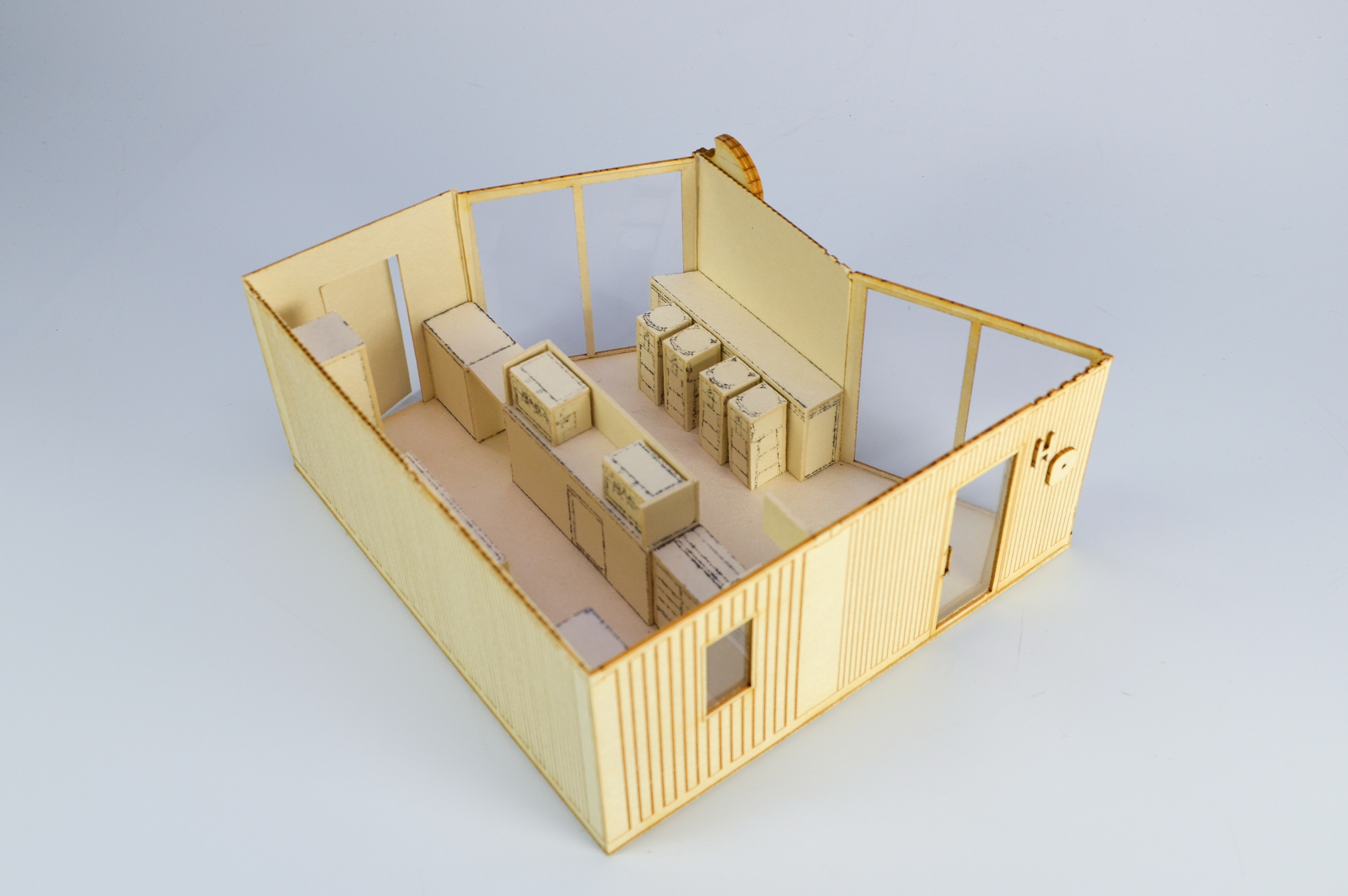 Miniature model of a room with yellow walls, wooden furniture, and multiple boxes or containers.