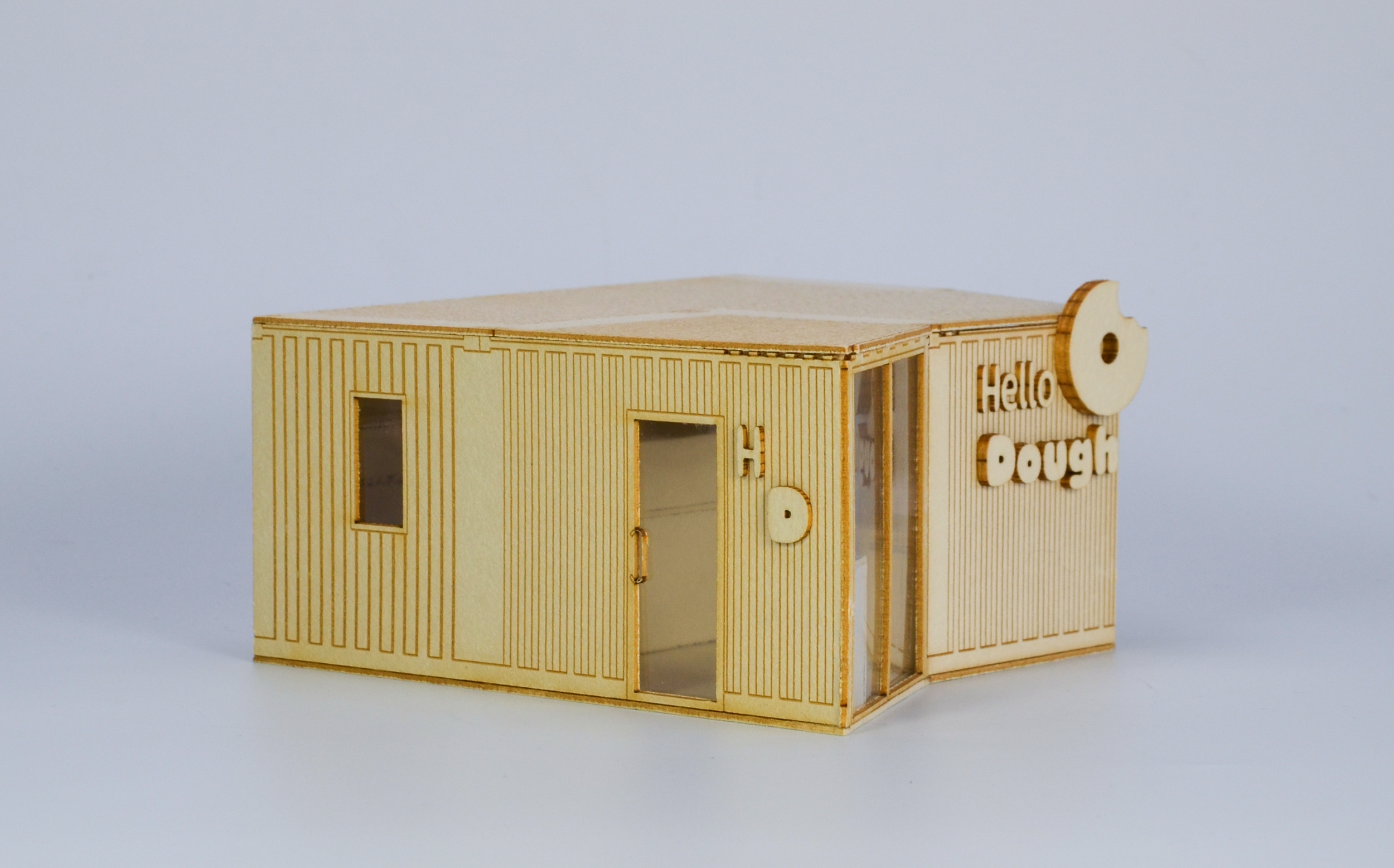 Small wooden model of a building with the words 'Hello Dough' and a large doughnut shape attached to the side.