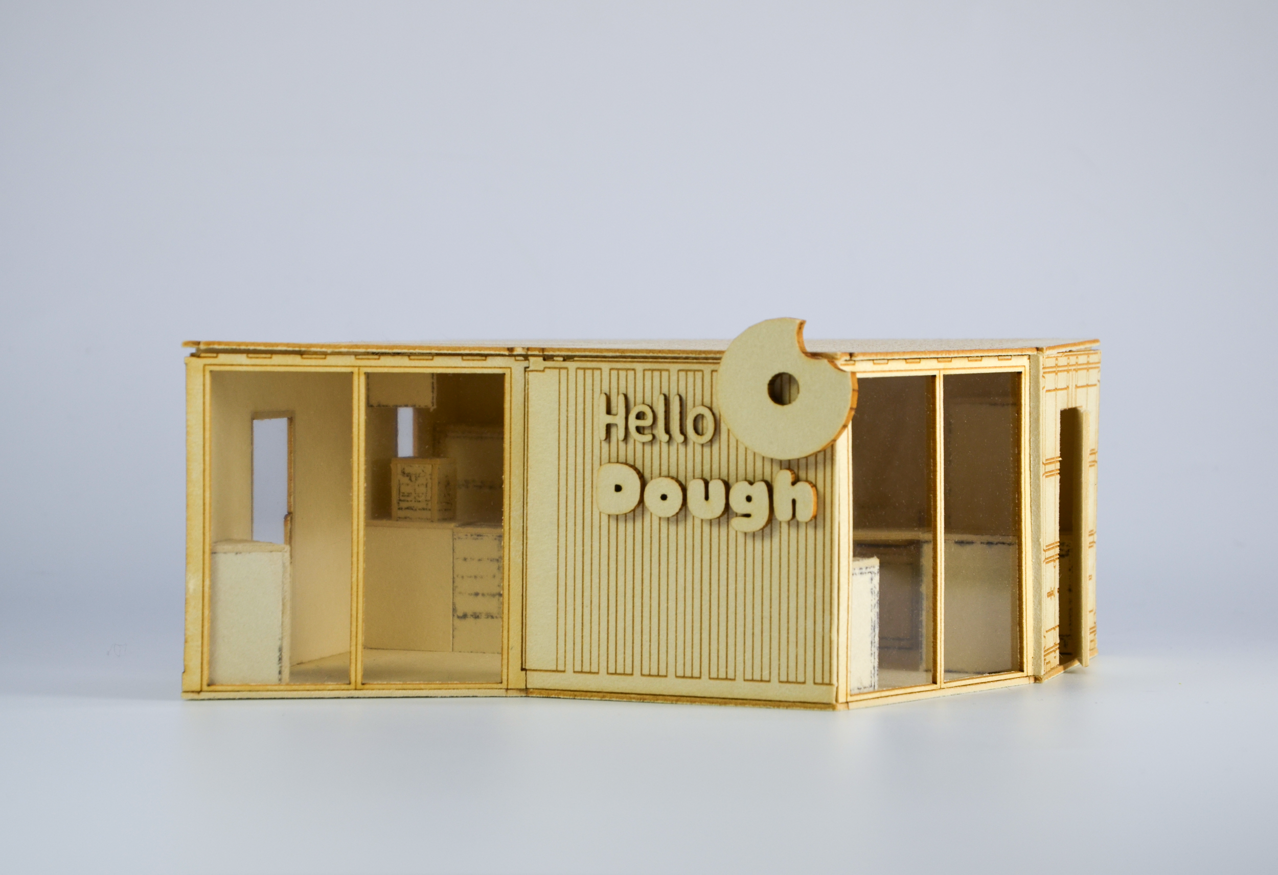 Miniature wooden dollhouse with the words "Hello Dough" on the front, empty interior with clear windows, isolated on a plain white background.