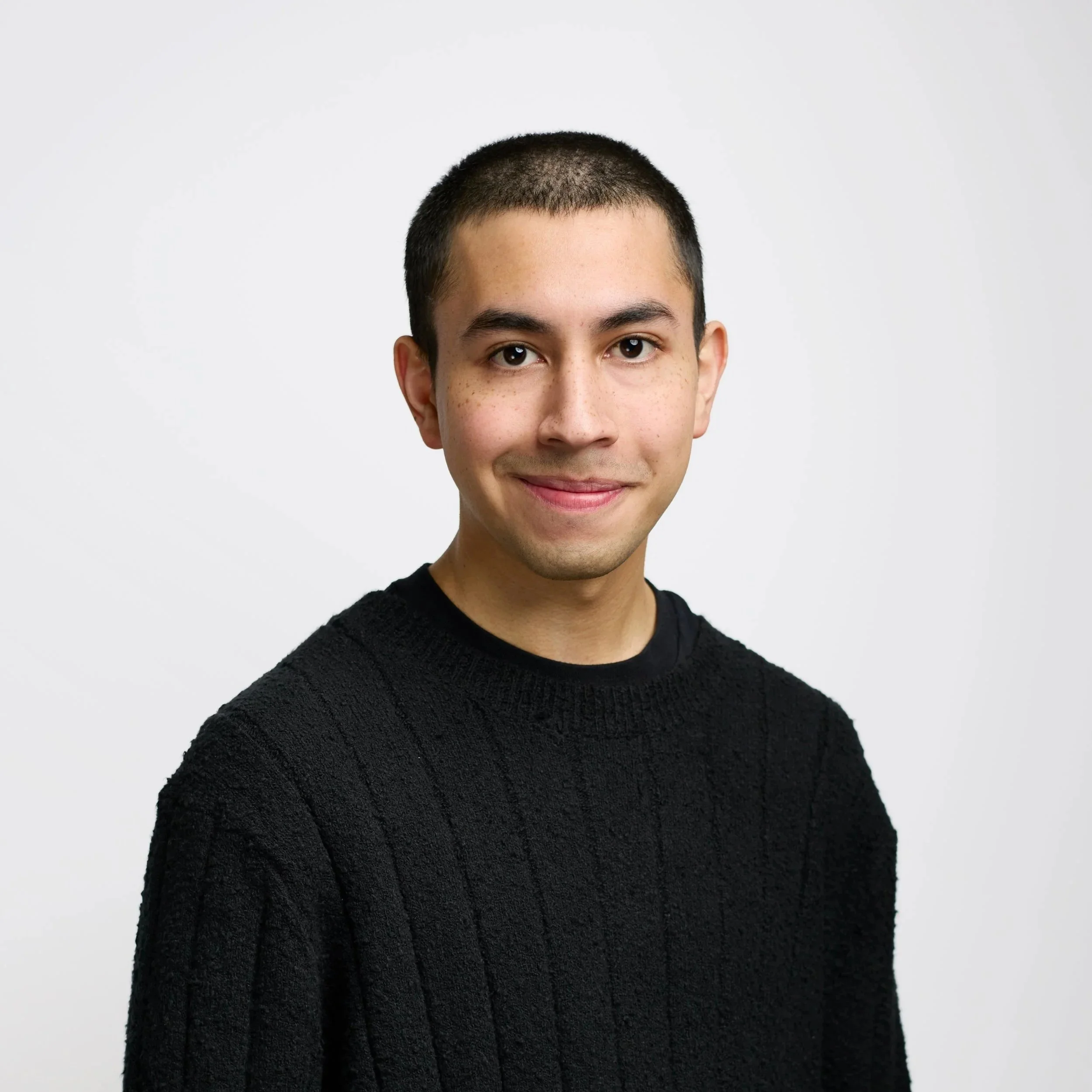 Portrait of a young man in a black shirt against a black background.