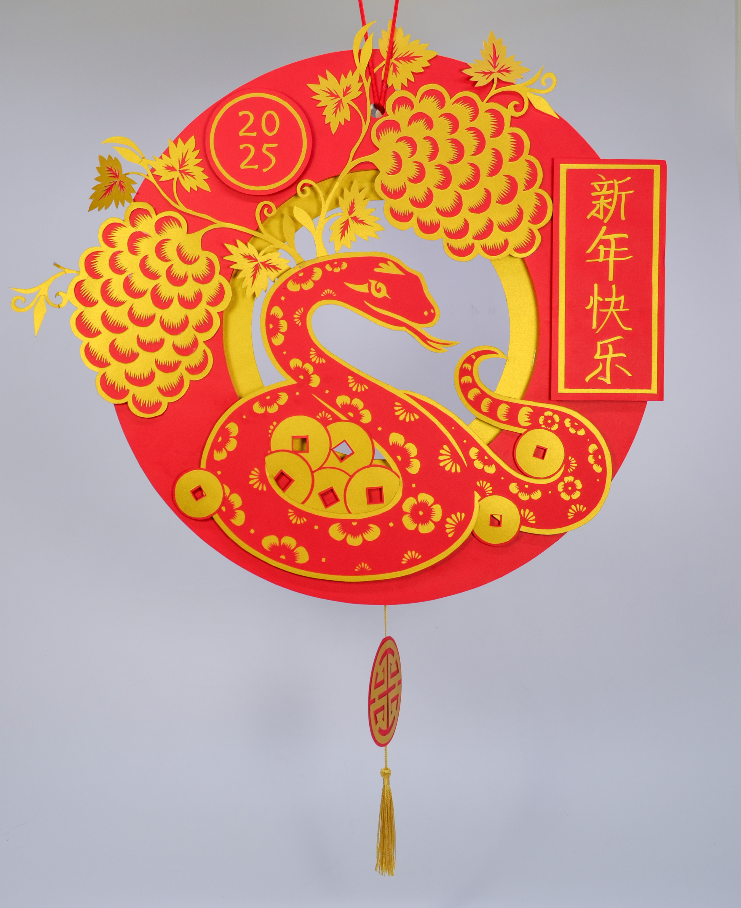 Red and gold decorative paper cutout celebrating the Year of the Dragon in 2024, featuring stylized dragons, grapes, and Chinese characters for "Happy New Year."