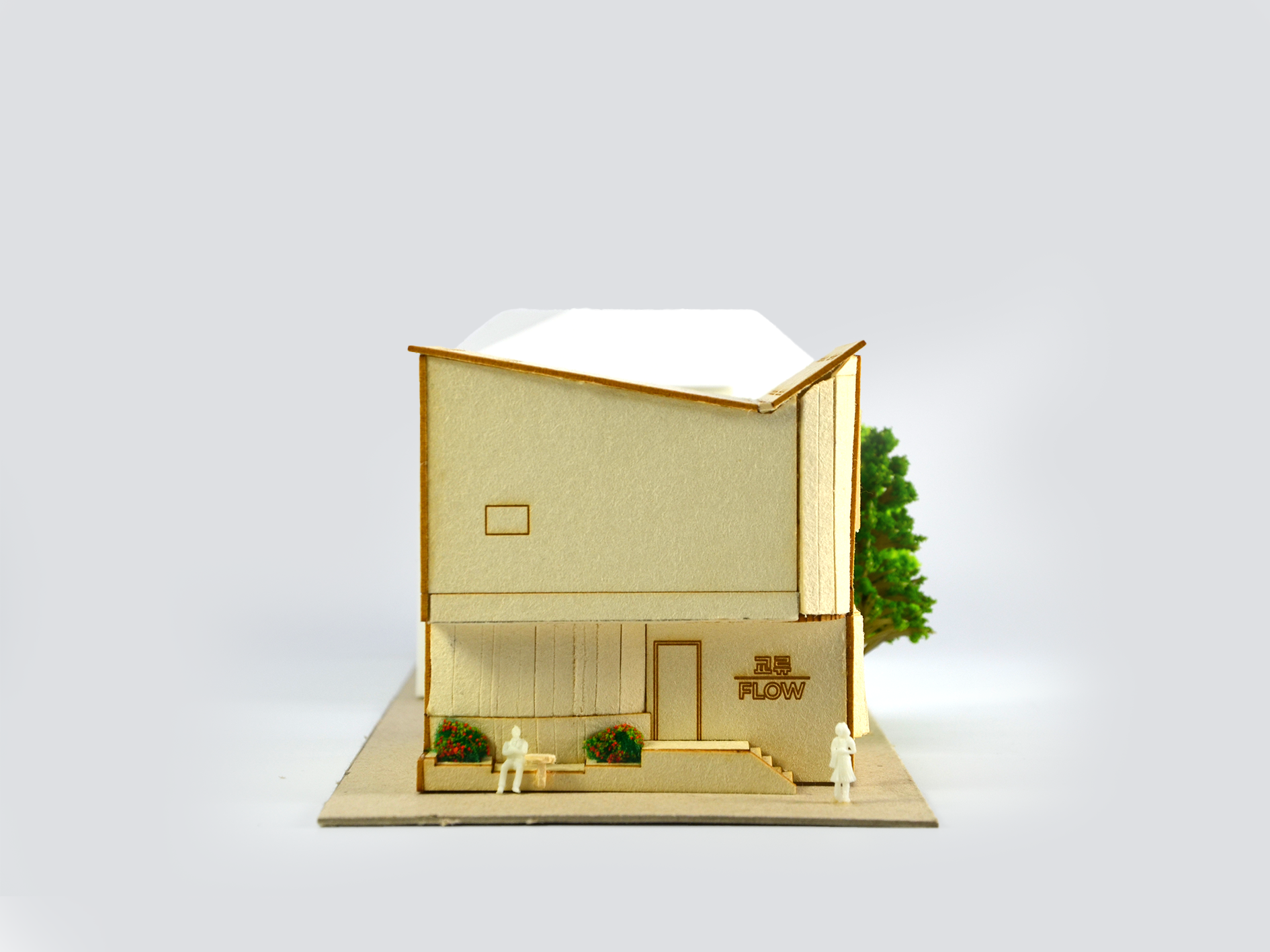 Miniature architectural model of a modern building with trees and small figurines in front, some with a sign labeled 'Flow'.