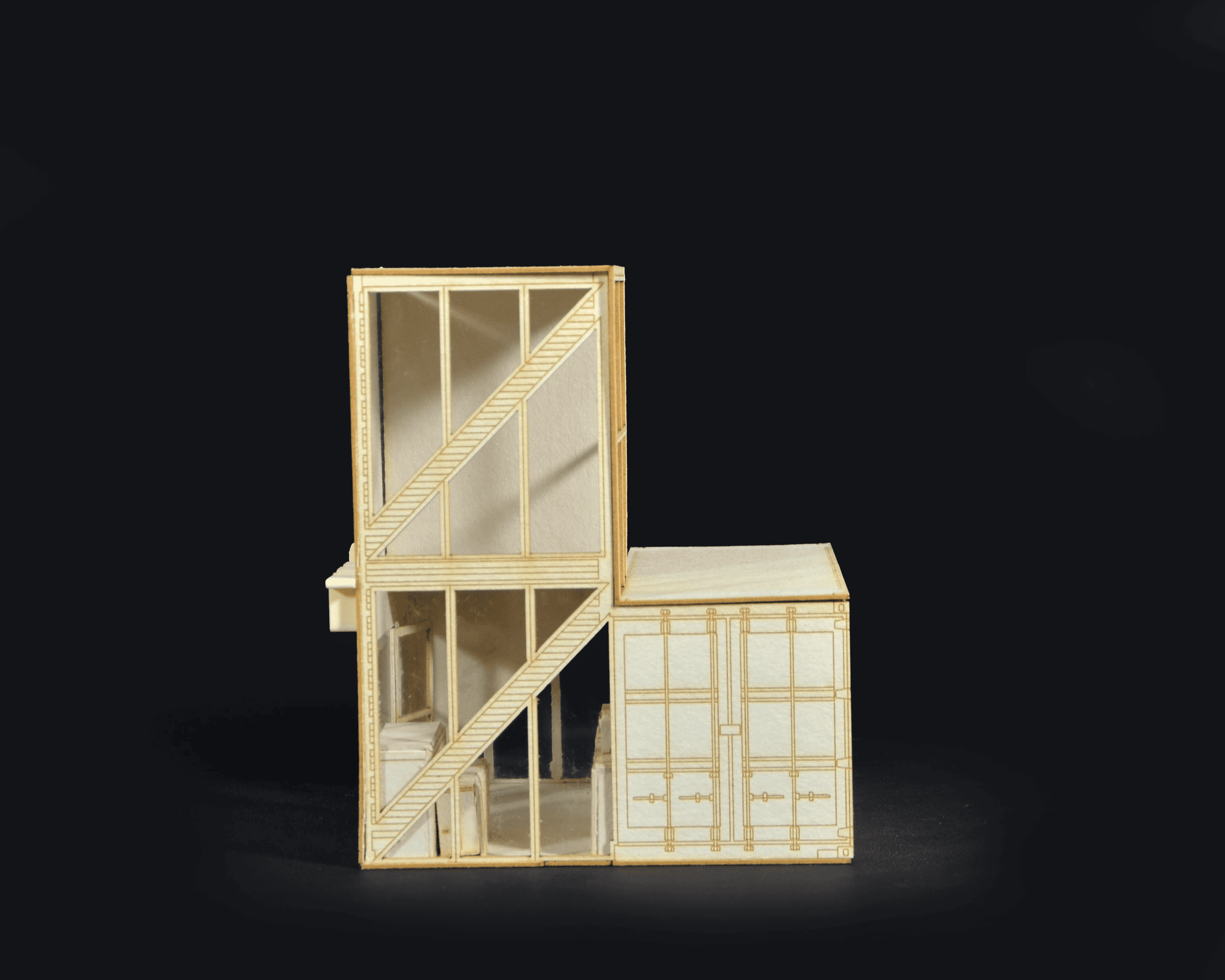A detailed architectural model made of thin wood showing multiple floors, walls, and stairs, set against a black background.
