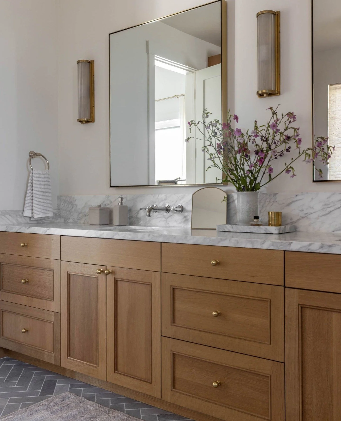 A well-designed primary bath should feel like a retreat, but function like a workhorse. In this space, we layered warm oak cabinetry, honed marble, and handmade tile to create texture and depth without overwhelming the senses. Wall-mounted faucets an