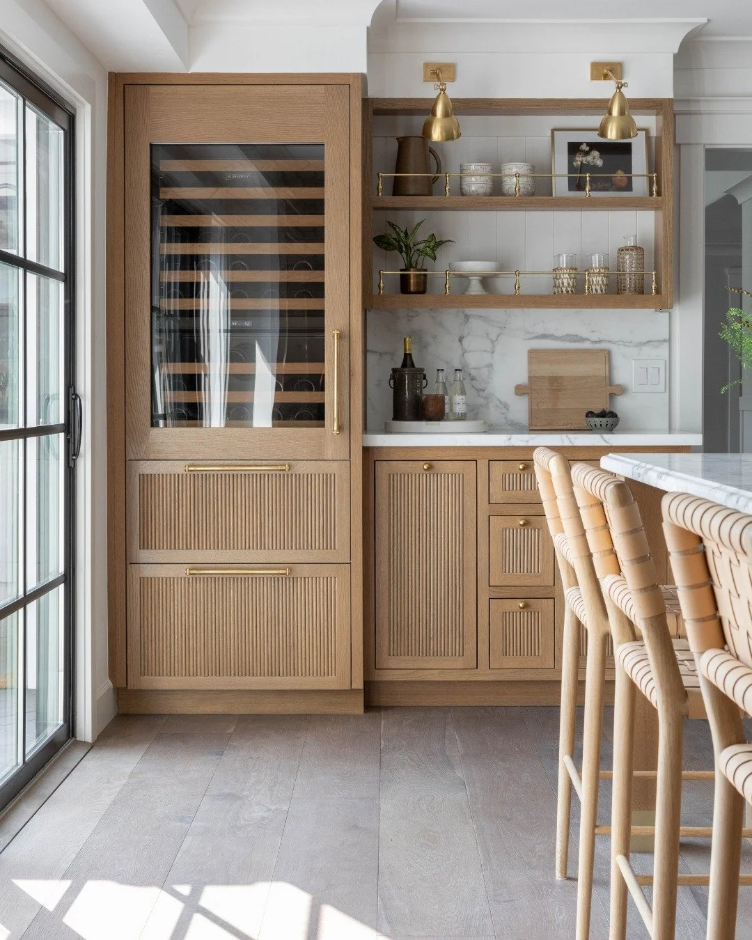 Not to be dramatic, but every home needs a bar moment like this. 🤎

This one was designed to work hard day to day, while still feeling beautiful. Fluted wood cabinetry, warm brass accents, and open shelving keep everything within reach &mdash; witho