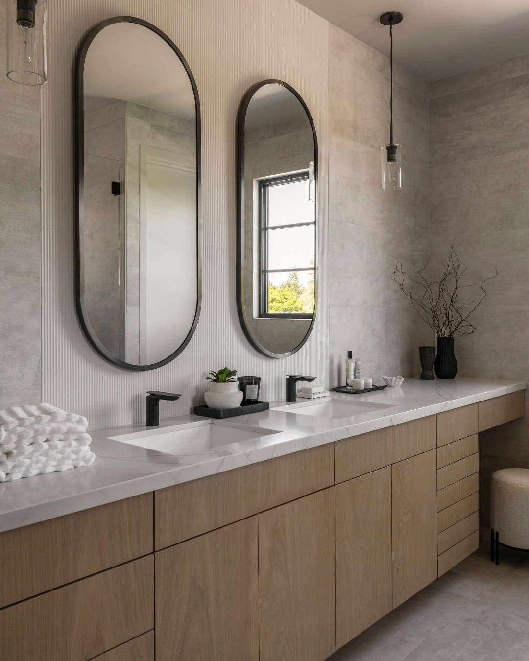 A neutral palette with plenty of dimension. 🤍

If you want to keep a bathroom feeling minimal and modern, contrast is key. Here, wood cabinetry, textured tile, and matte black accents add depth without taking away from the simplicity of the space.

