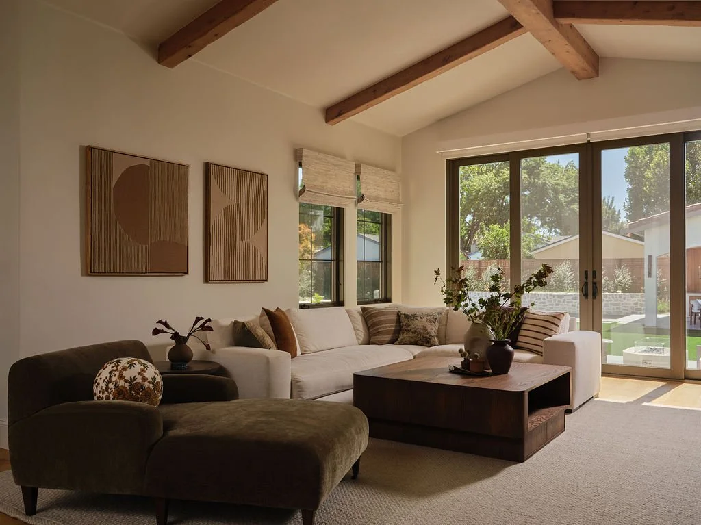 Warm Mediterranean living room with exposed wood beams, layered neutral furnishings and indoor-outdoor connection