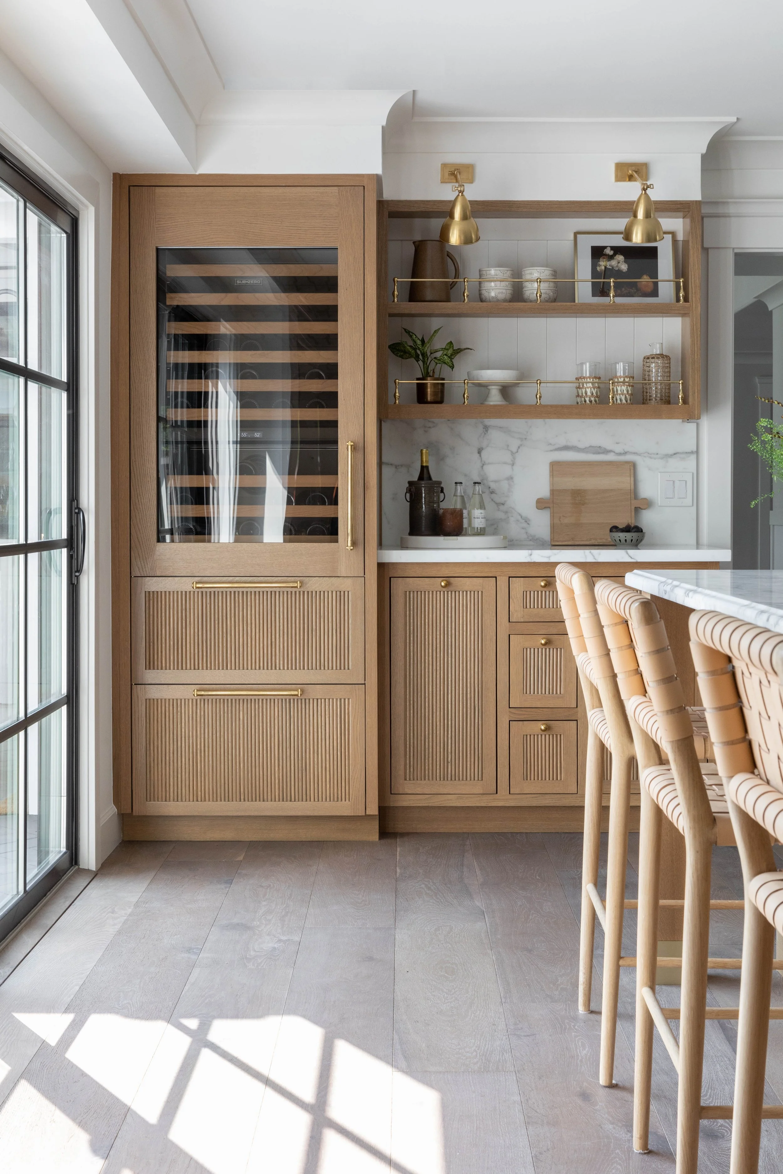Custom wood bar cabinetry with wine storage, marble backsplash and brass details