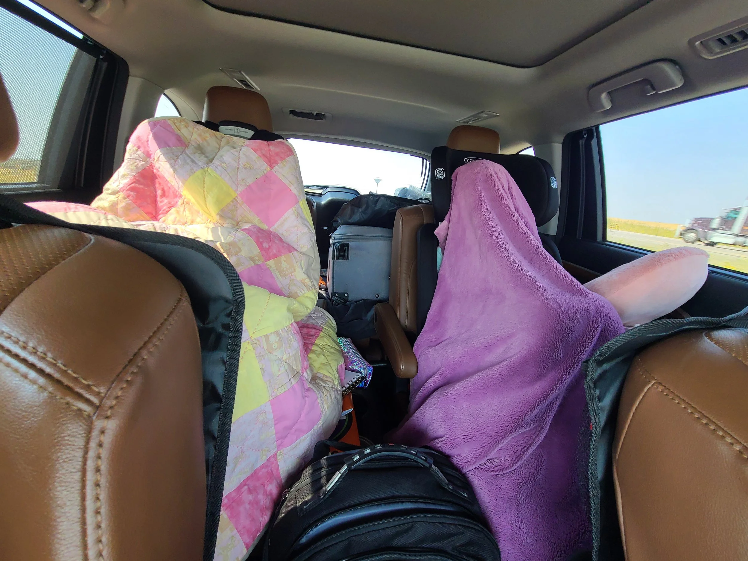 Kids on a family road trip wrapped in blankets