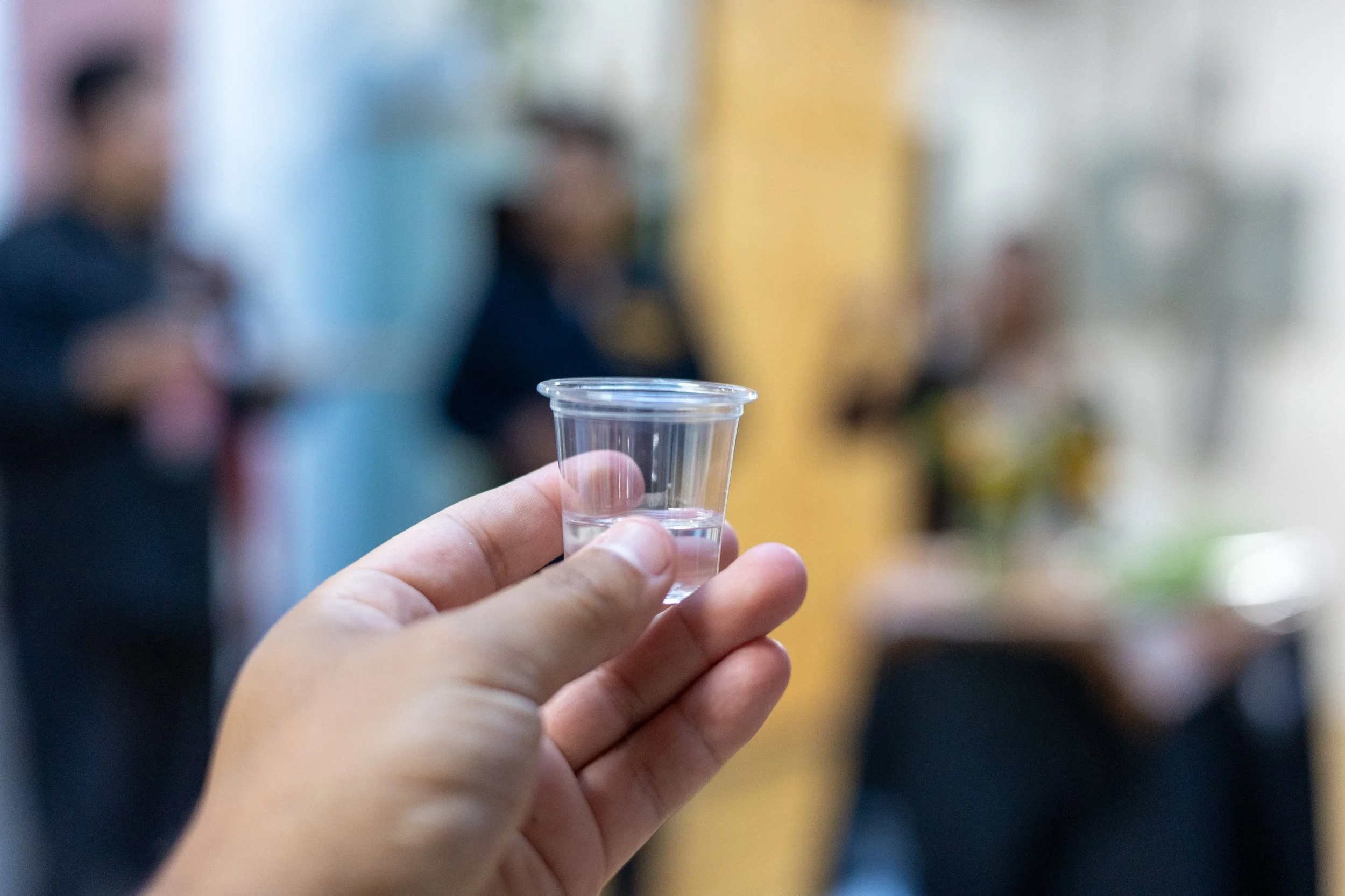A hand holding a shot of mezcal.