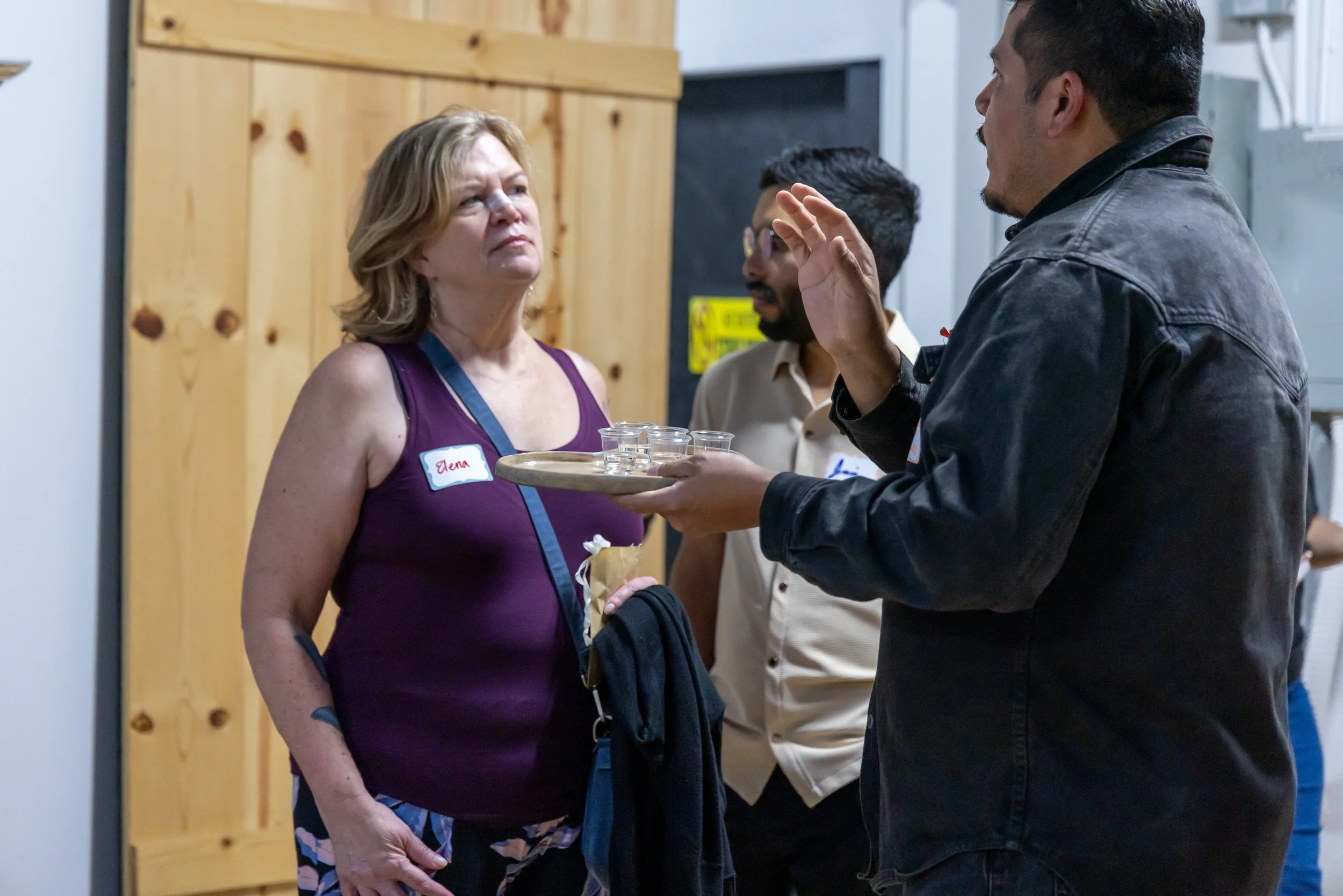 Padrino carrying mezcal and talking with guest.