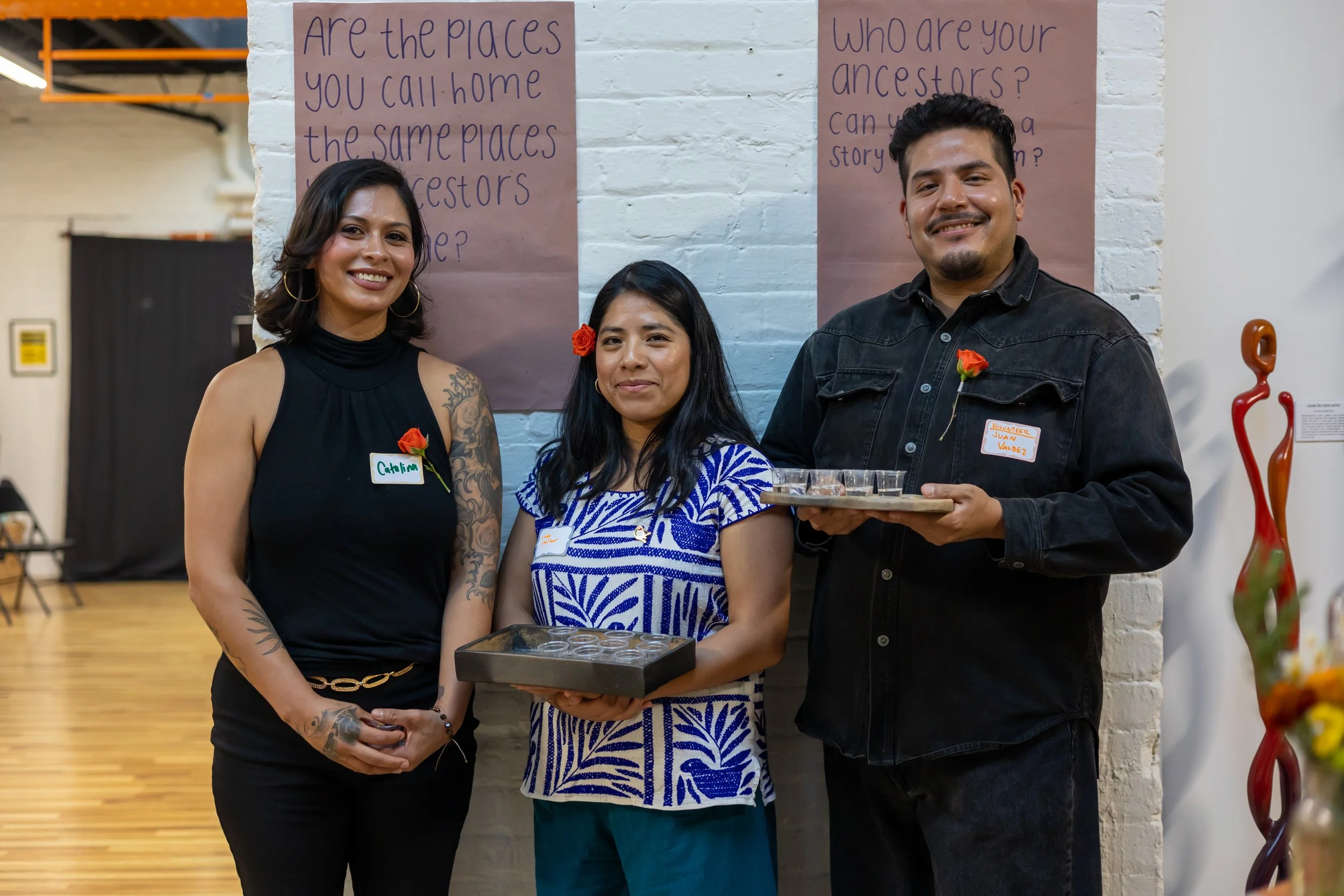 Madrinas and padrino hold trays with mezcal. 