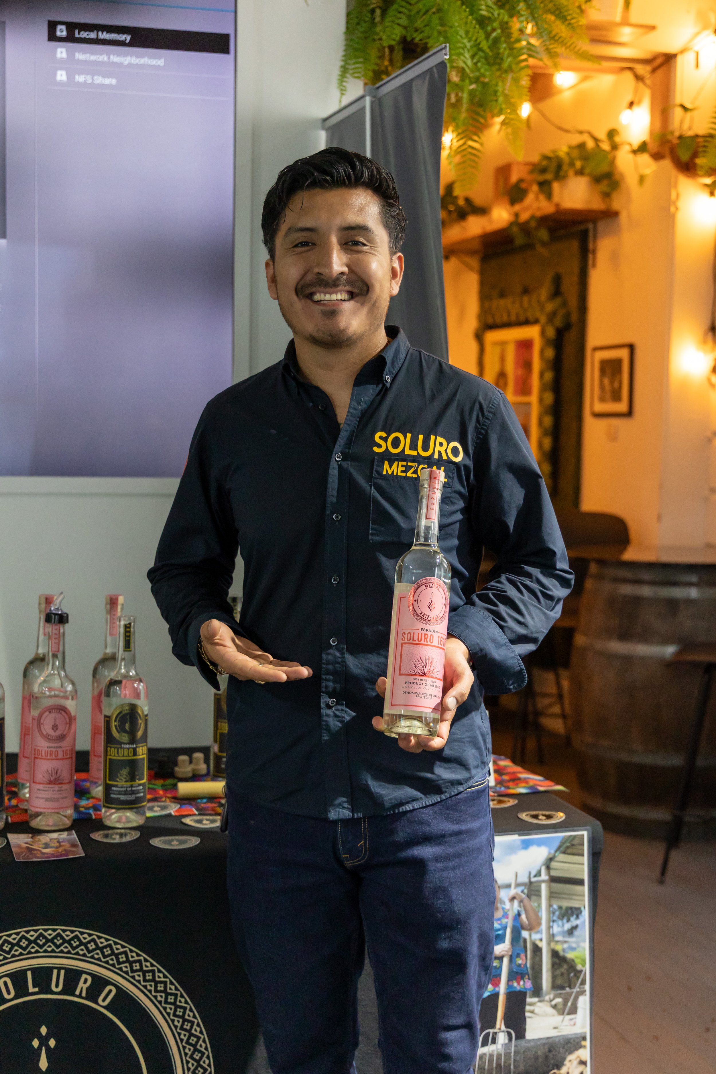 Luis Humberto holding a bottle of his mezcal brand, Soluro. 