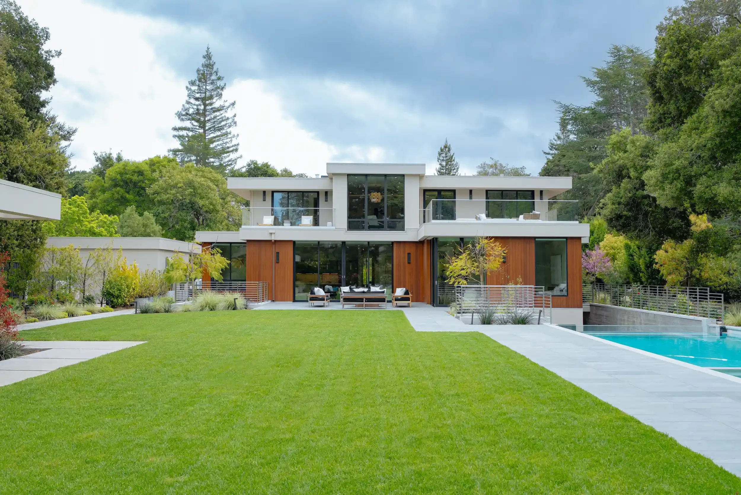 Real estate photography in the Bay Area featuring a modern luxury home with large glass windows, landscaped garden, and outdoor pool.