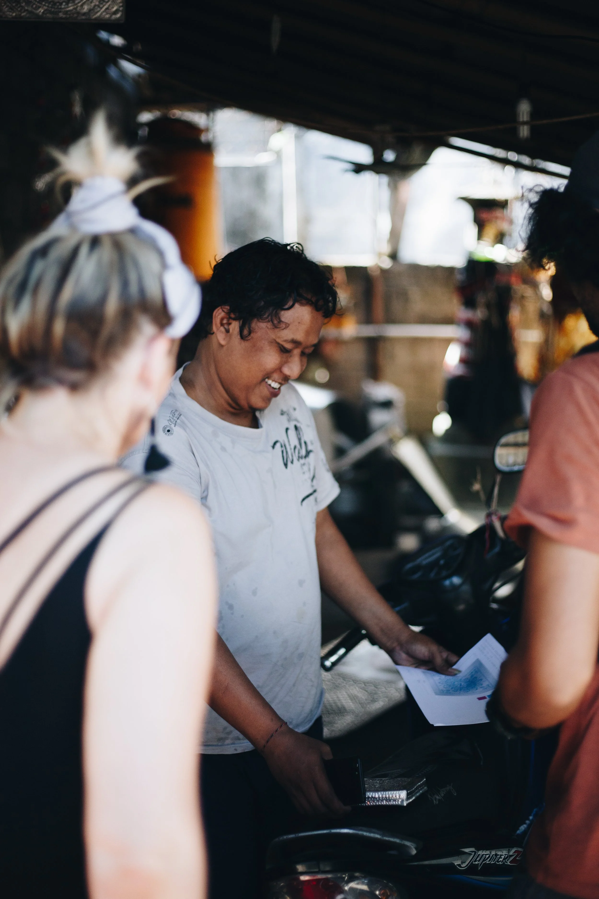 People gathered around a man smiling while holding papers in an indoor setting.