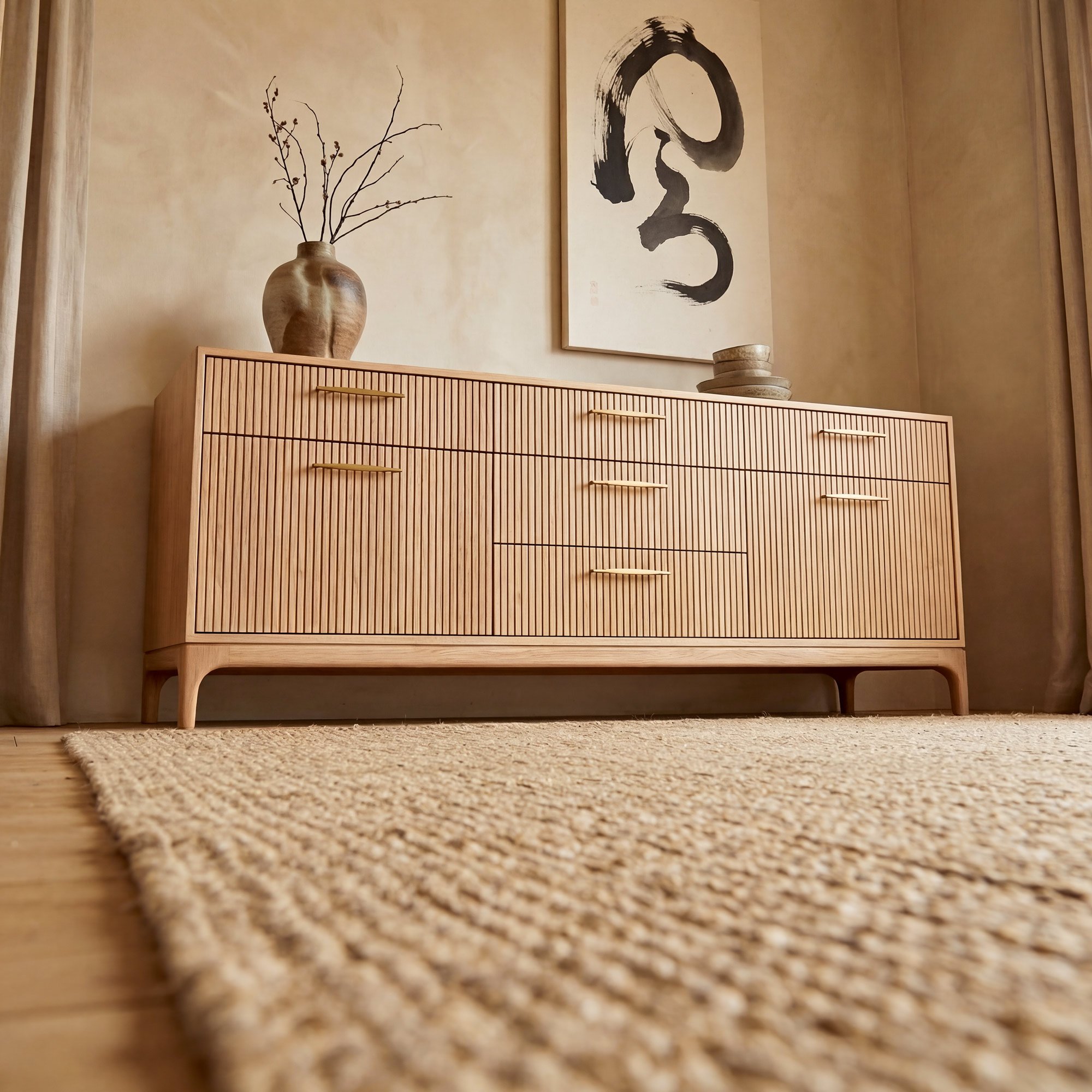 Solid timber sideboard in American white oak with grooves on the front, 7 solid timber drawers and round/curved legs with a frame and brass handles