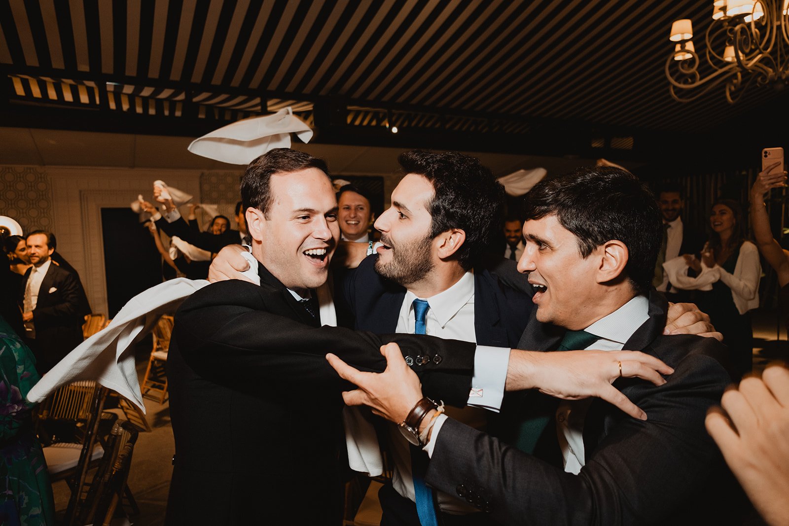 Hombres en traje celebrando alegremente con pañuelos en una fiesta.