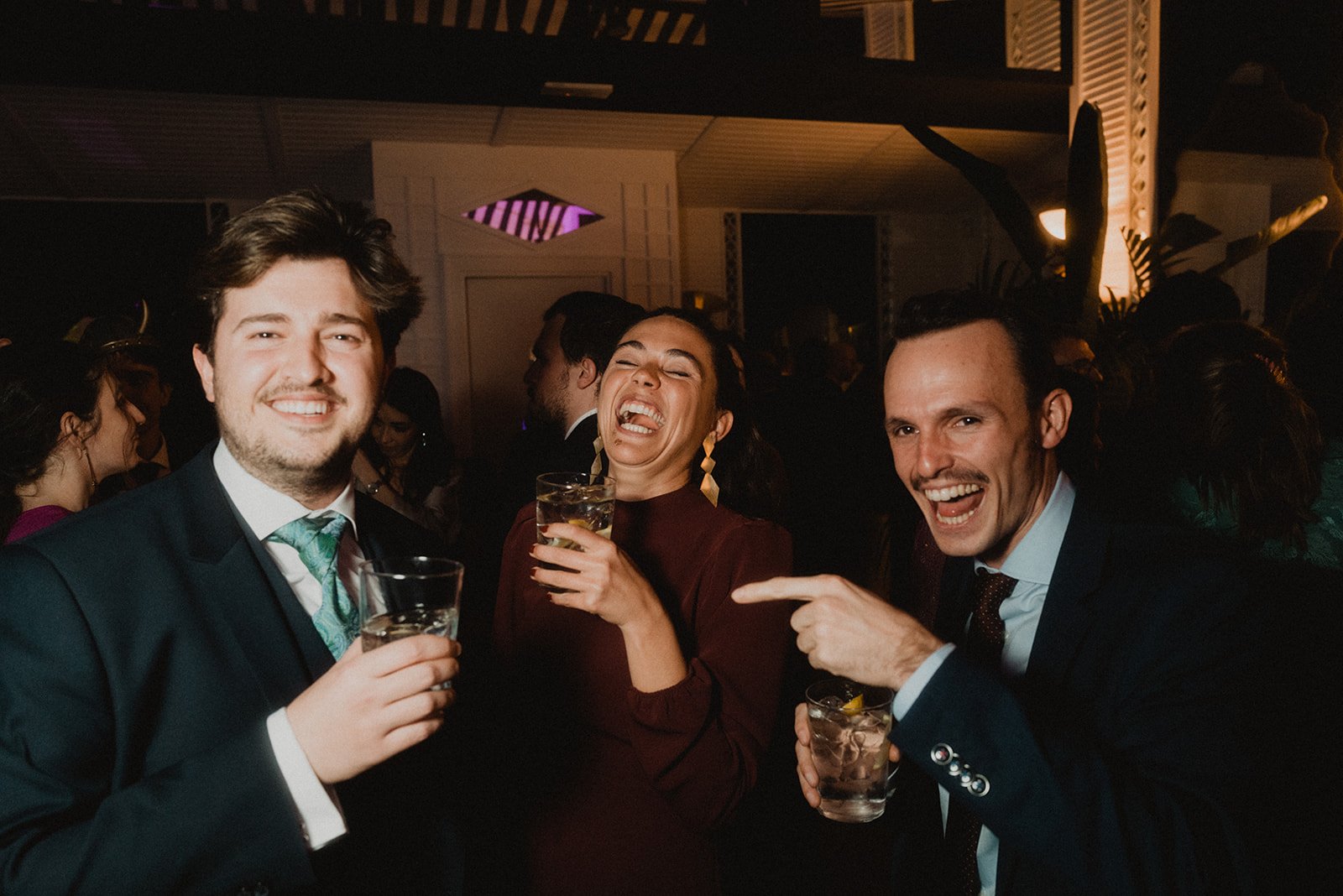 Un grupo de personas en una fiesta, sonriendo y sosteniendo bebidas.