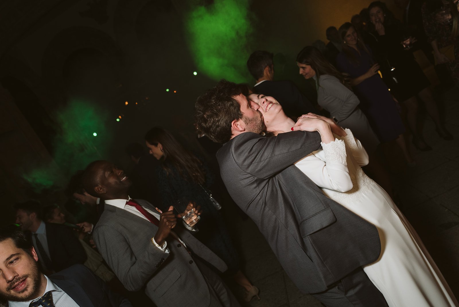 Personas bailando en una fiesta con luces verdes y ambiente festivo.