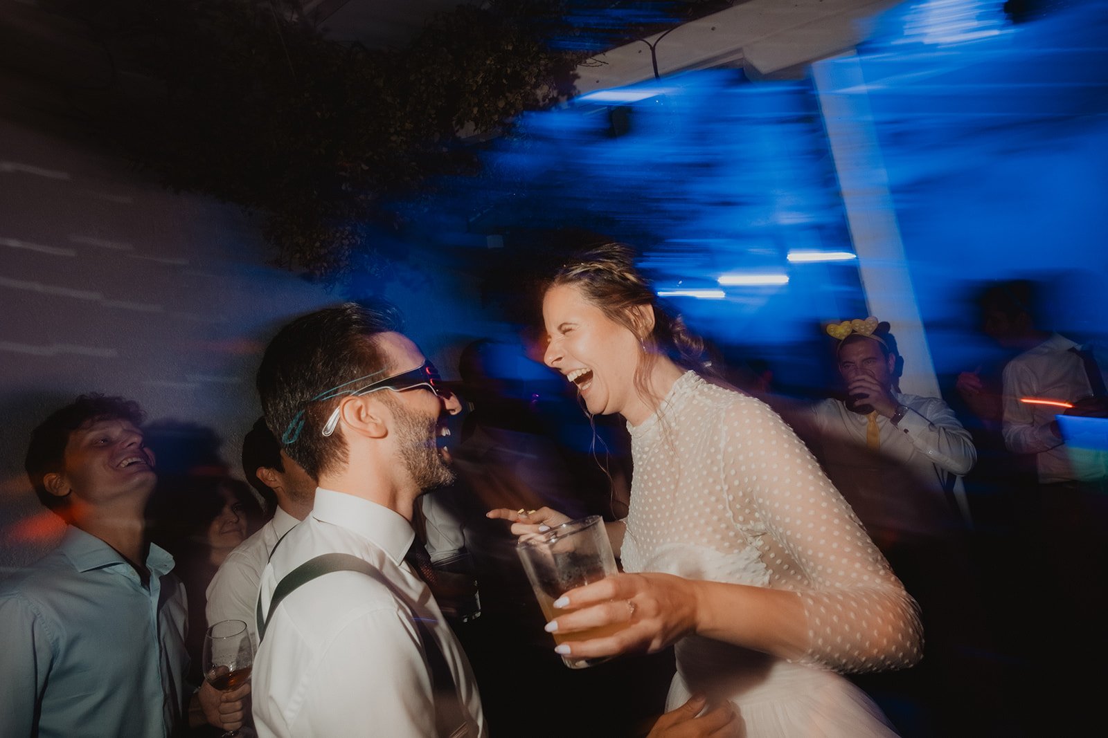 Personas sonriendo y disfrutando en una fiesta con luces azules.
