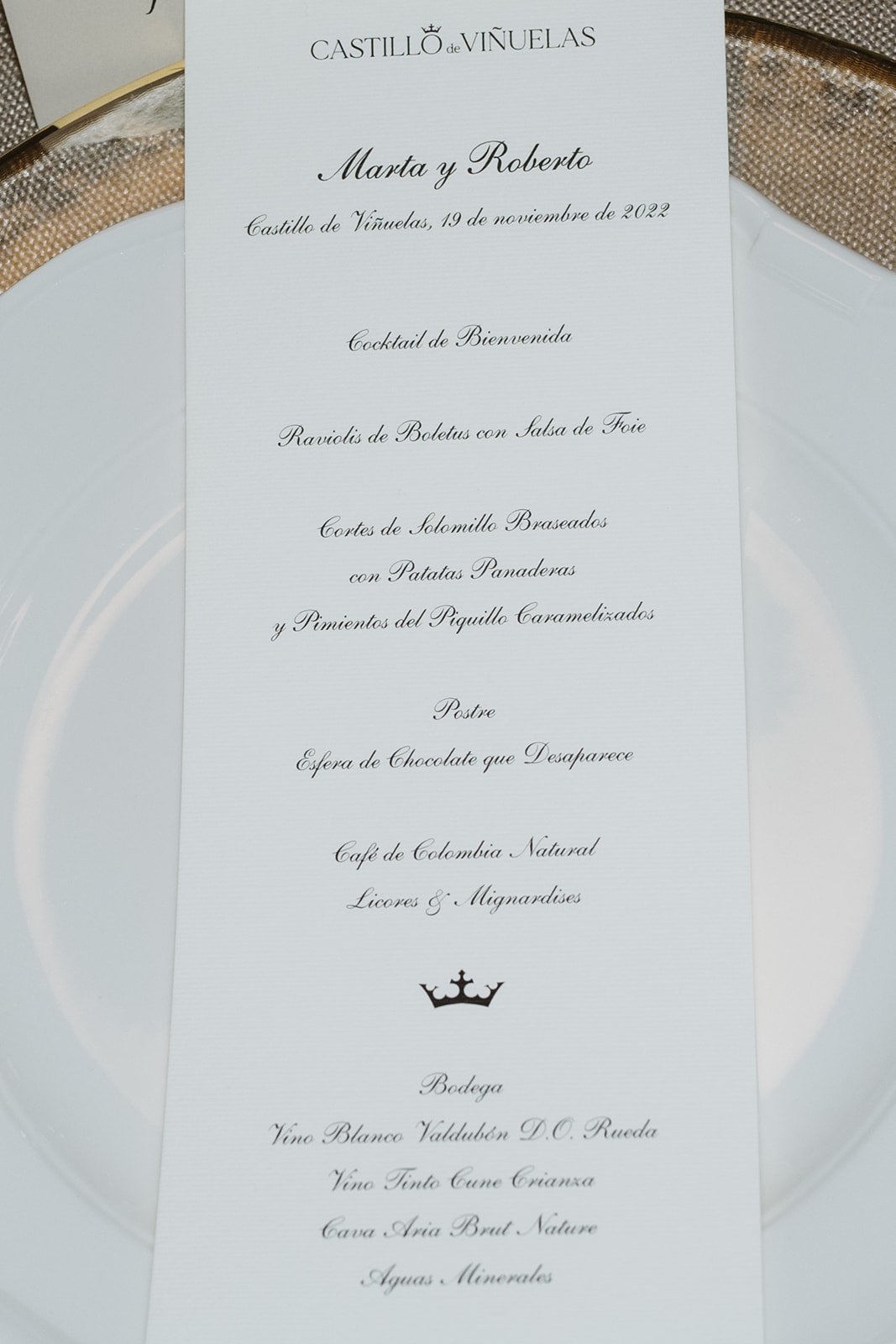 Menú de boda impreso con platos y bebidas; incluye raviolis de boletus, solomillo braseado y esfera de chocolate. Vinos, café y licores también mencionados. Ubicación: Castillo de Viñuelas.
