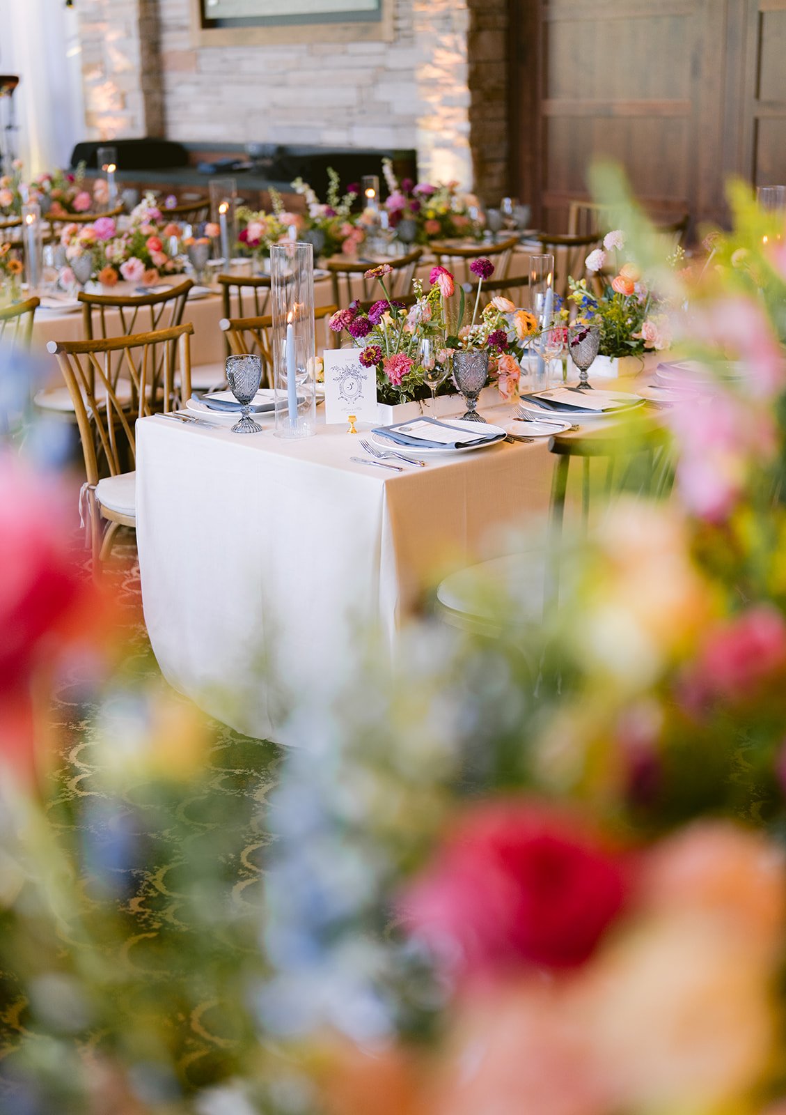 Elegant table setting with floral centerpieces and glassware at a wedding or event venue. Maui wedding planner.