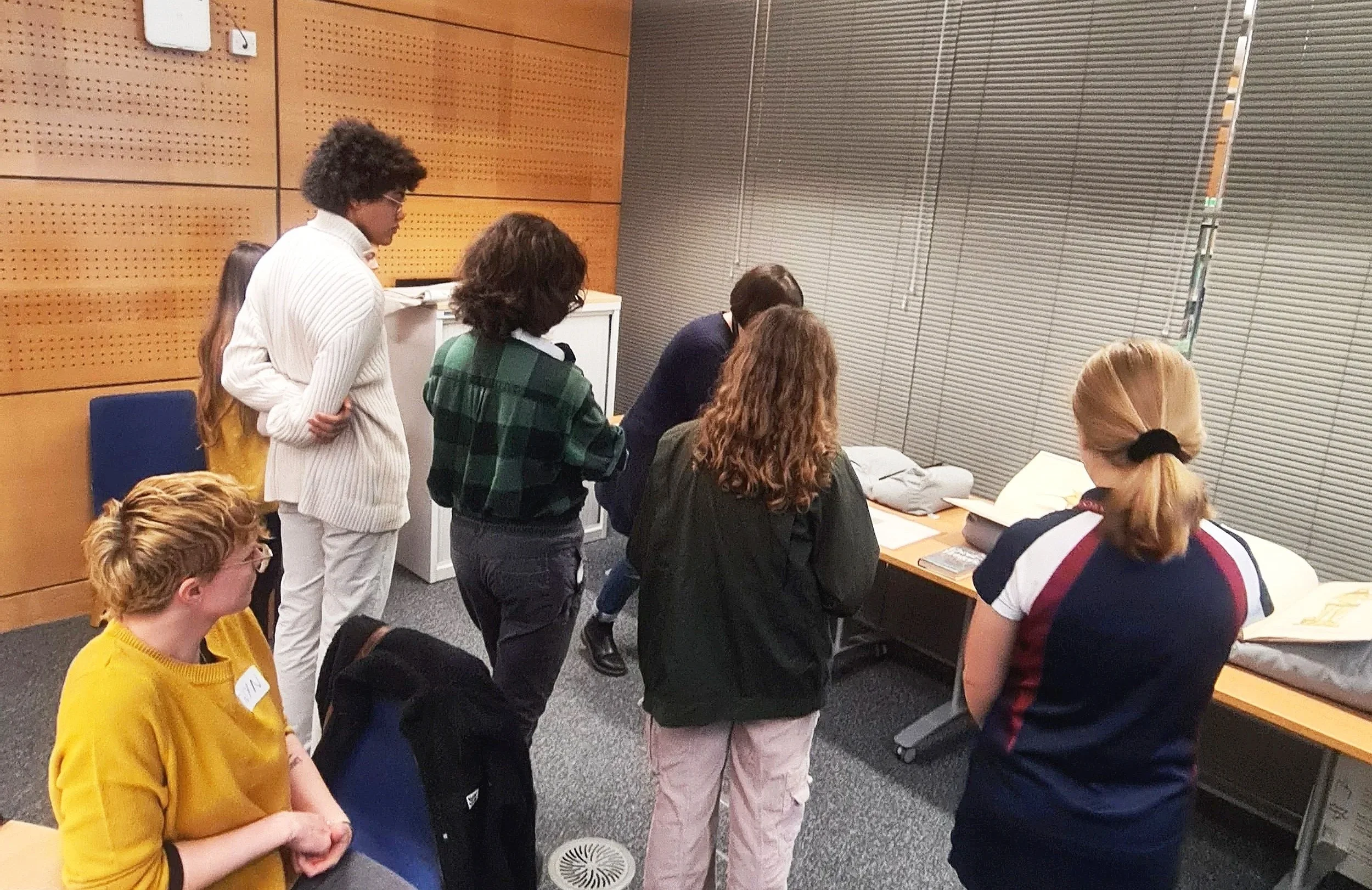 A group of young people look at a collection of historical artefacts in the library.