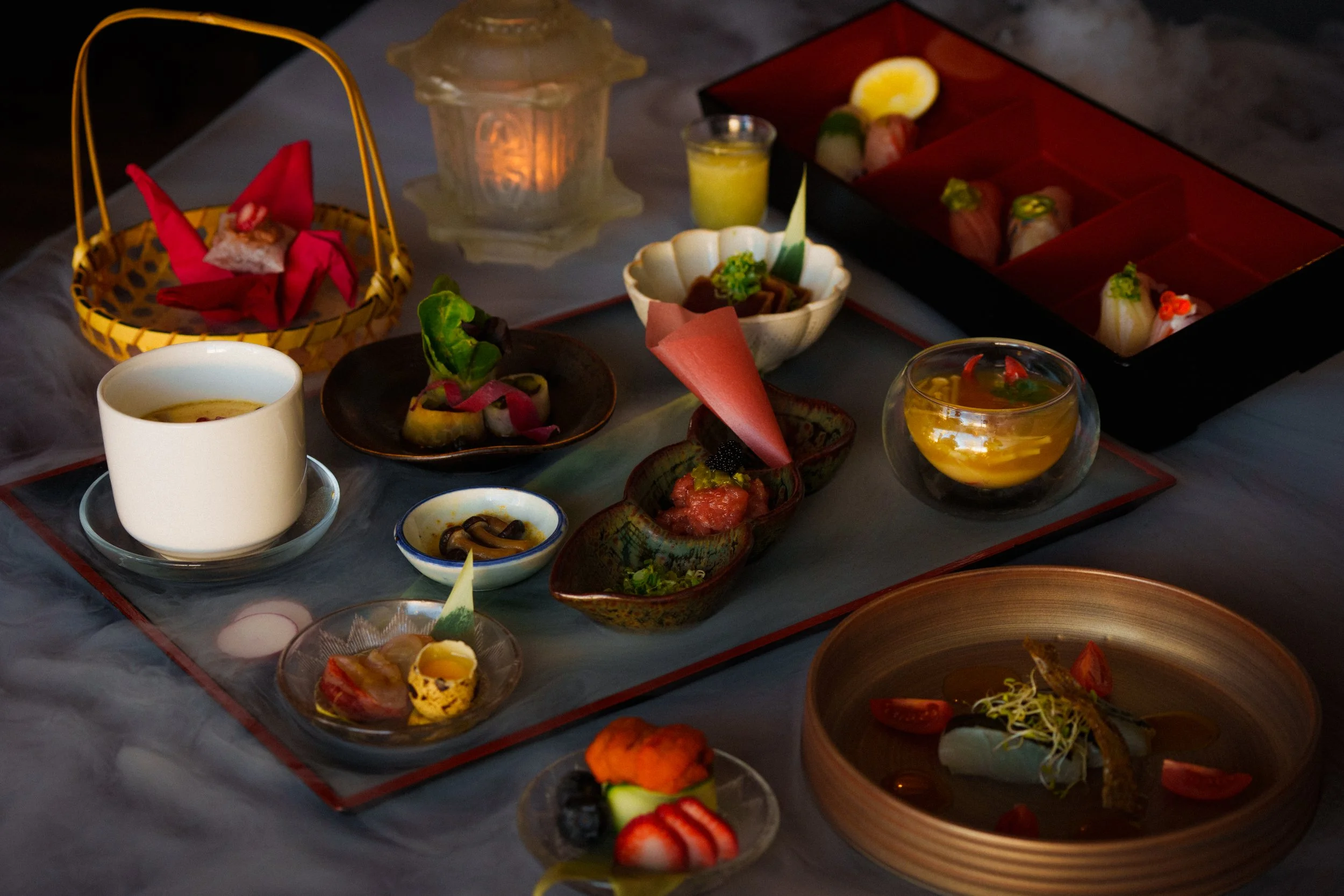 Kaiseki Japanese dinner and desserts on a table, including sushi, fruit, and small appetizers, with decorative presentation.