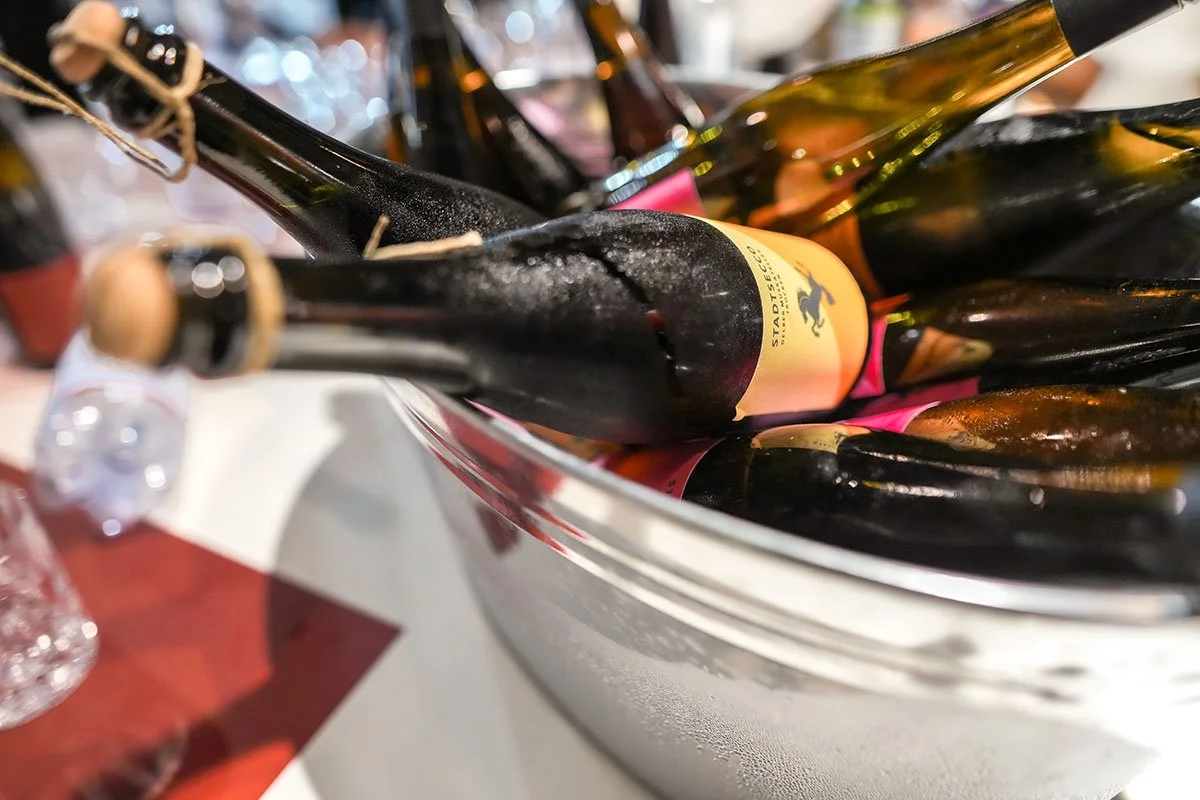 Eine Metallschüssel mit mehreren Flaschen Champagner, einige mit Korken verschlossen, auf einer Tafel