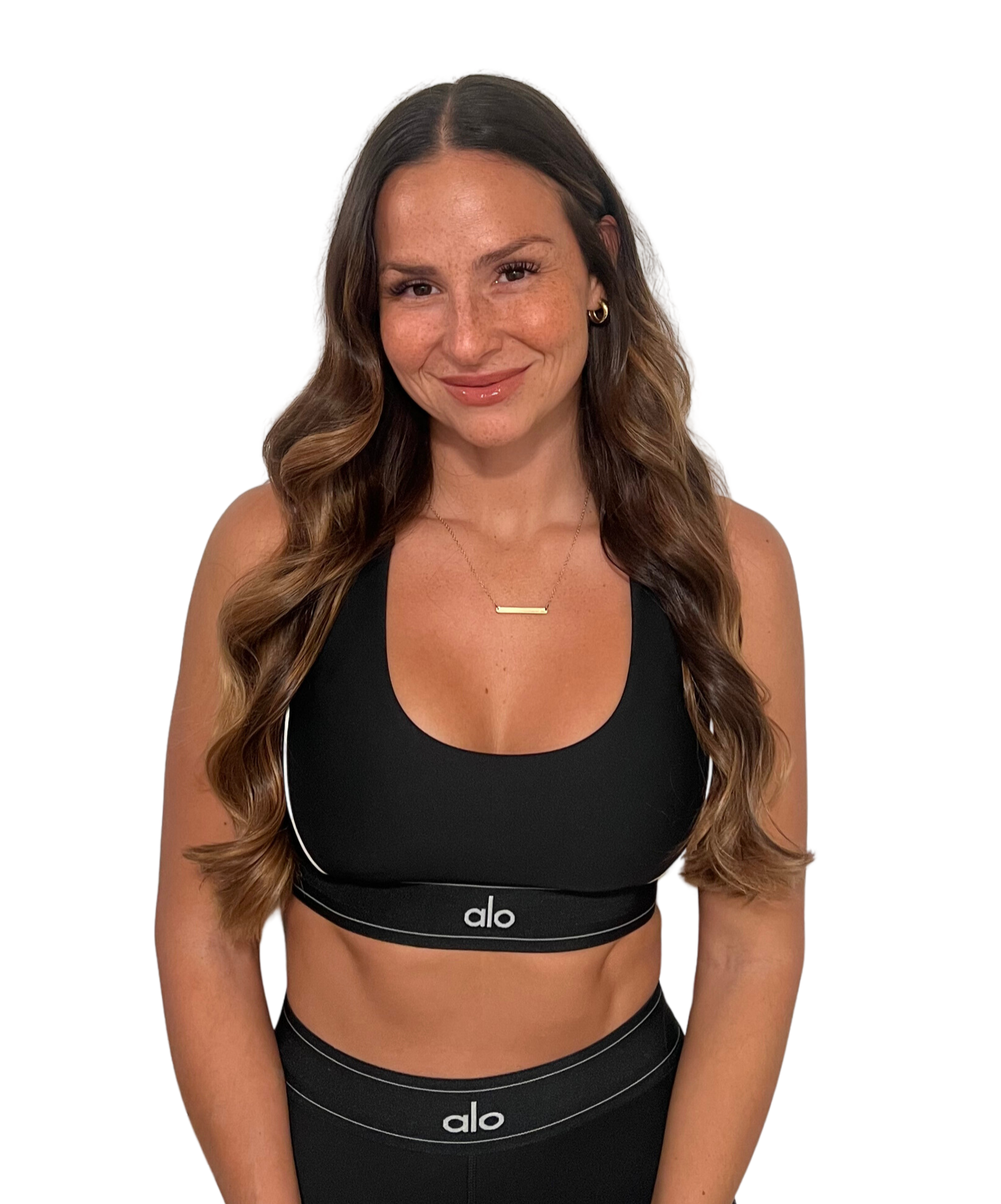 Smiling woman in black athletic wear, posing against a white background.